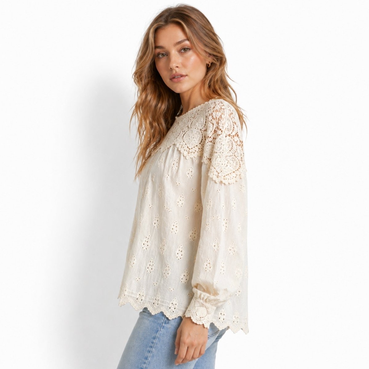 Side profile of woman in effortless bohemian off-white eyelet balloon sleeve top featuring intricate lace scalloped cuffs