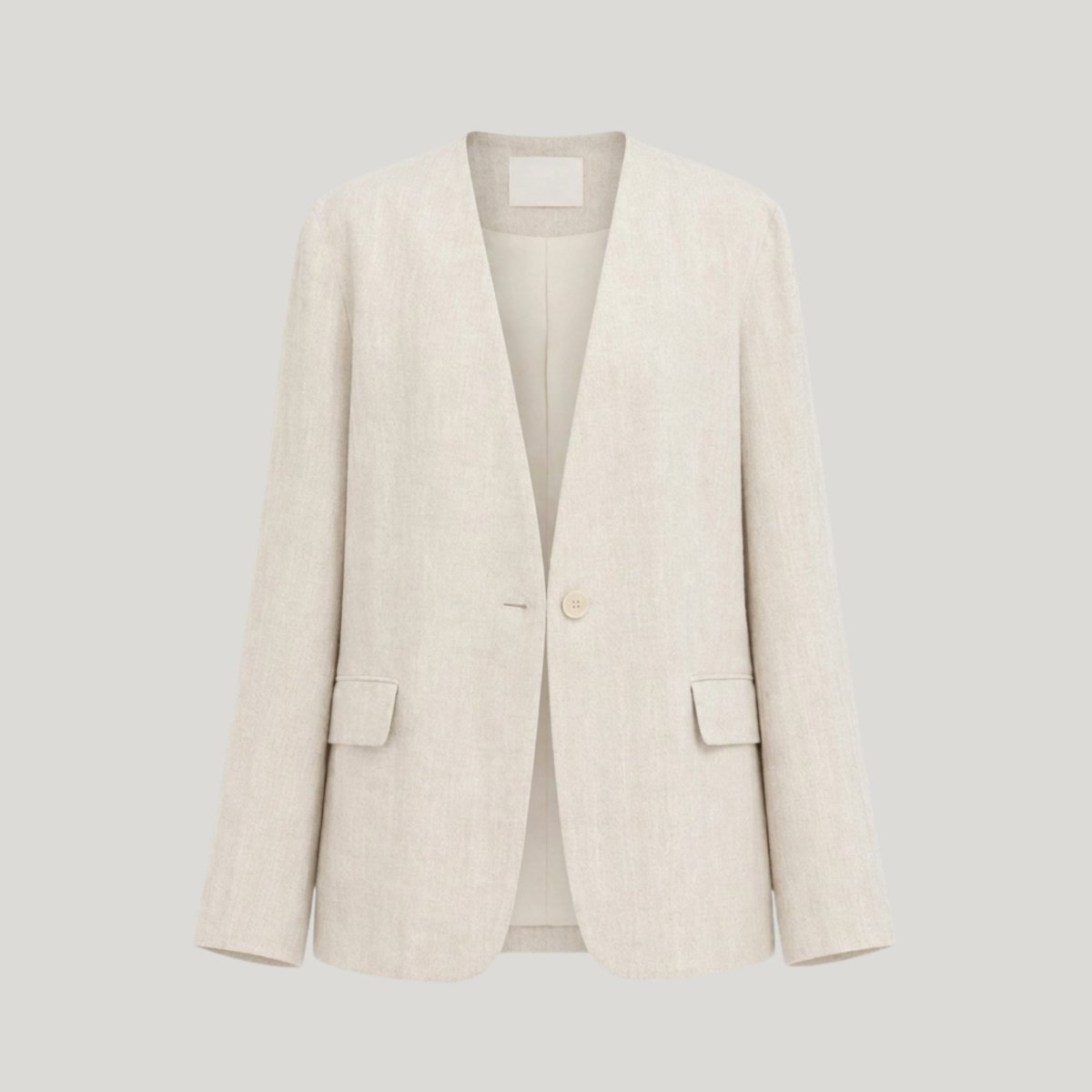 Flat lay ghost mannequin view of a beige collarless v-neck suit jacket showing front button details.