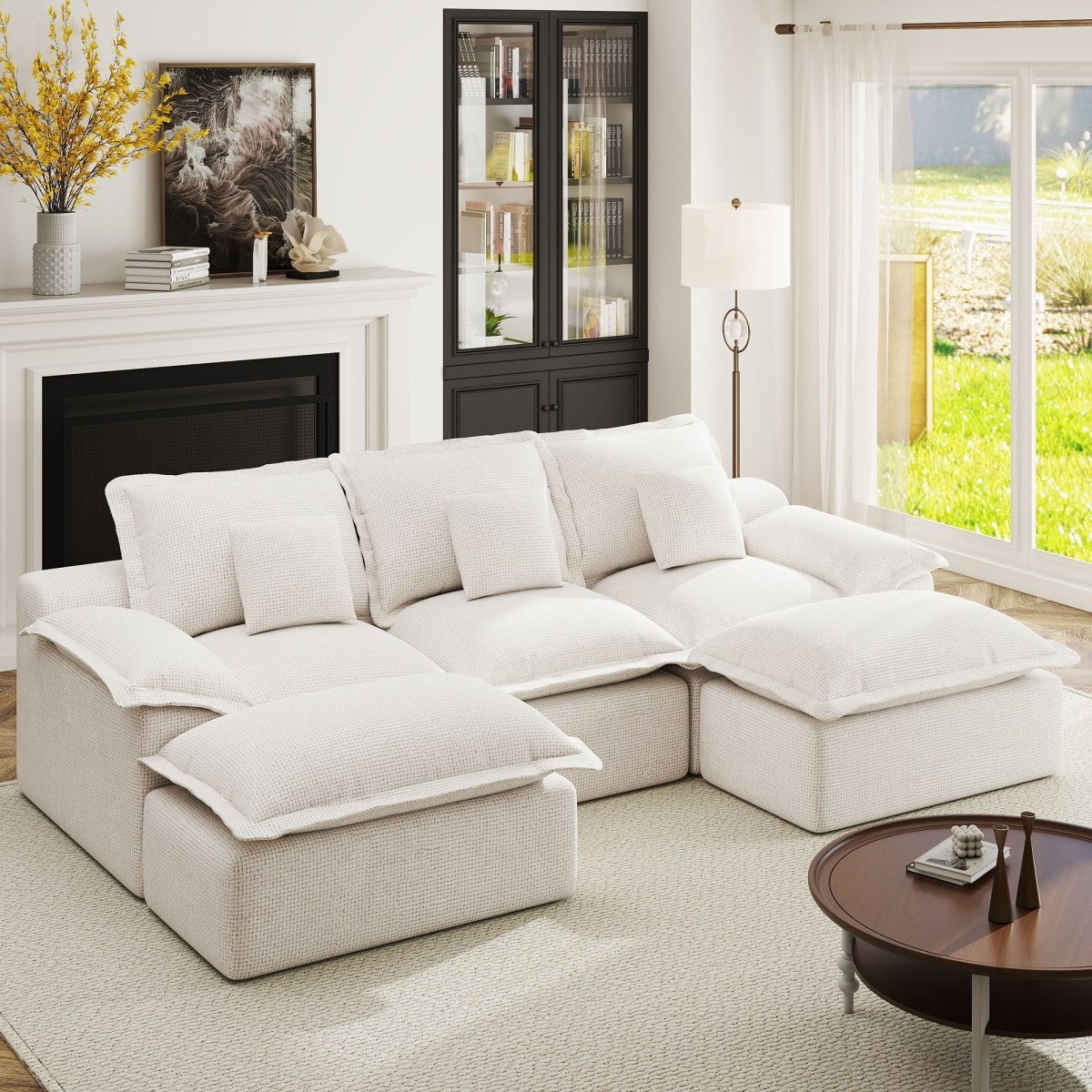 Cream-colored modular sectional sofa with two ottomans and plush cushions in a bright, modern living room.