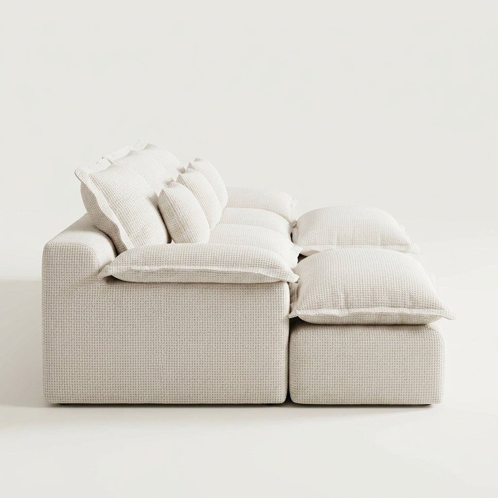 Side profile of a beige modular sofa showing the thick, overstuffed back cushions and soft corduroy-style texture.