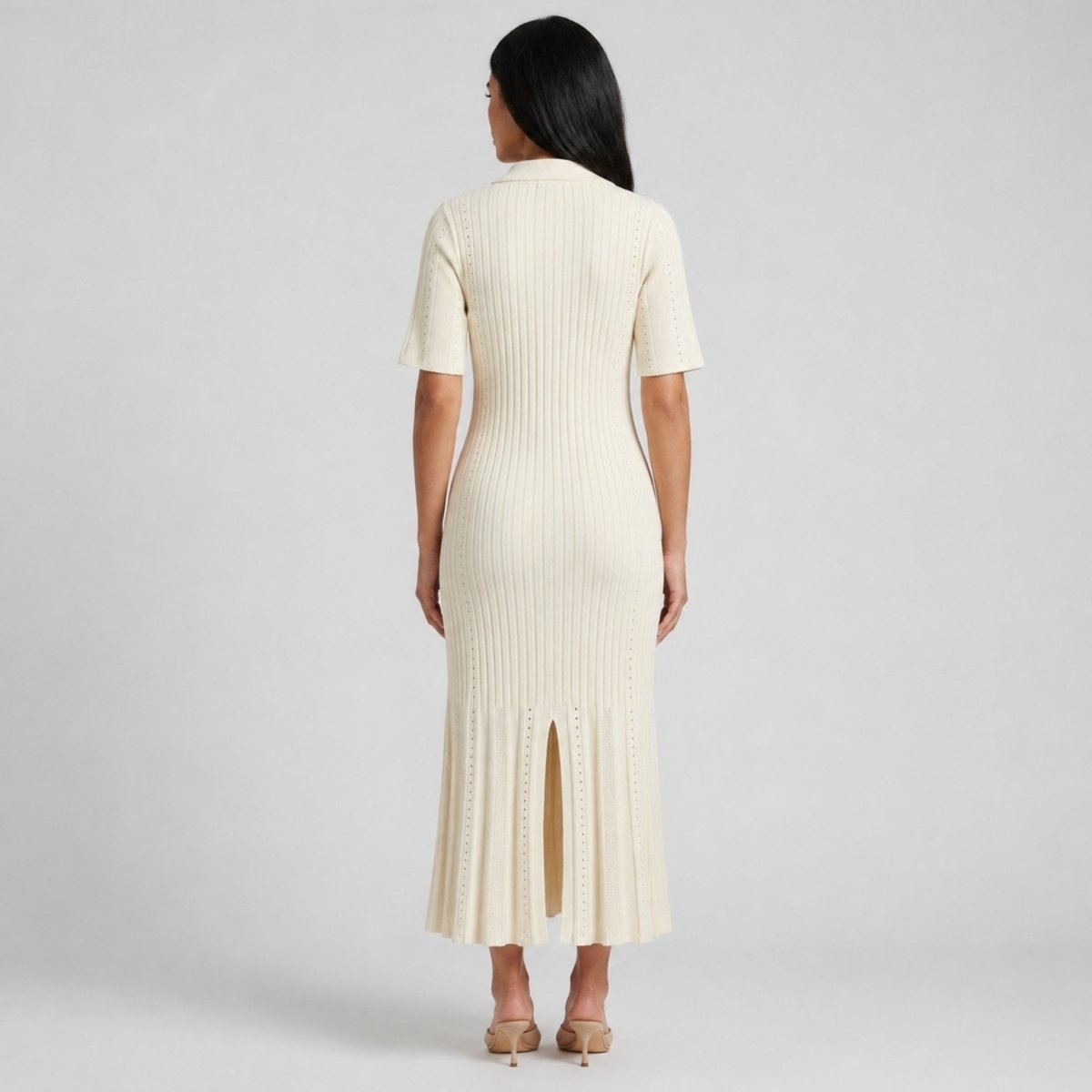Back view of woman wearing Kouvr beige pointelle knit sweater dress showing back slit detail.
