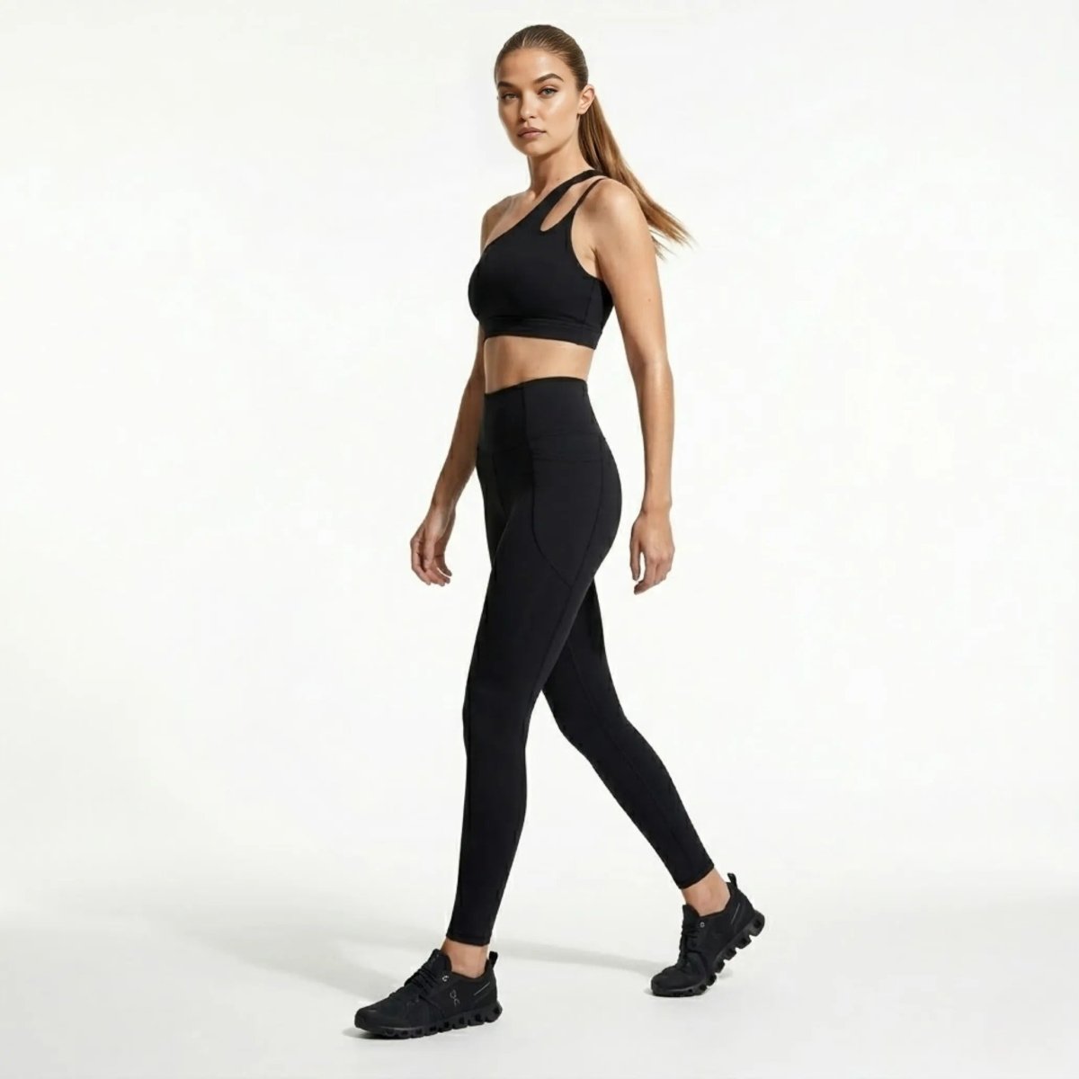 Woman walking in Kouvr black high waisted workout leggings with side pockets and cutout sports bra side view