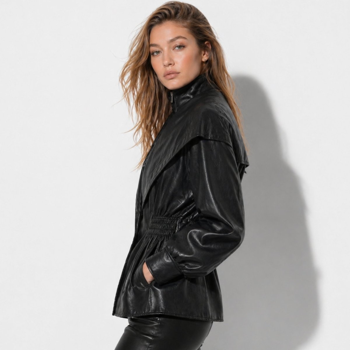 Side profile of woman in black faux leather balloon sleeve jacket with functional pockets from Kouvr.