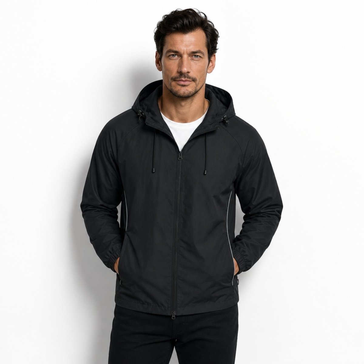 Man modeling Kouvr black water-resistant athletic jacket with hood down and hands in pockets.