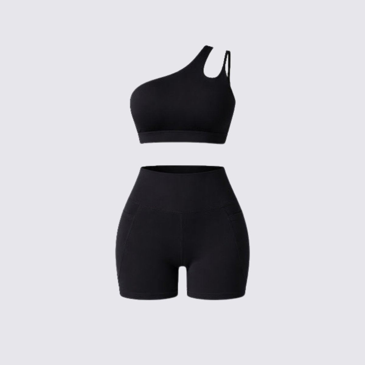 Flat lay of Kouvr black luxury activewear set showing one shoulder sports bra with cutout and high waisted pocket biker shorts