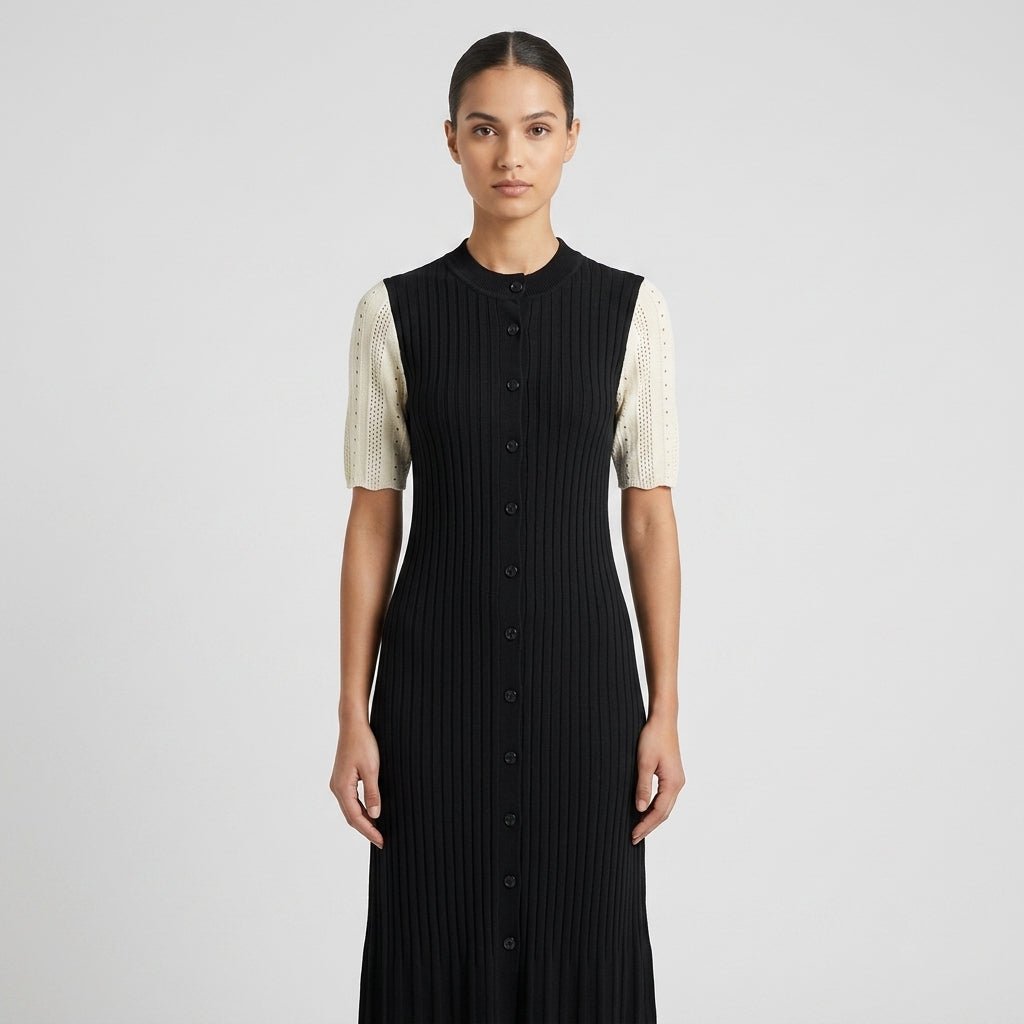 Close up view of the Kouvr black ribbed knit dress highlighting the high crew neck, front button details, and textured cream pointelle sleeves.