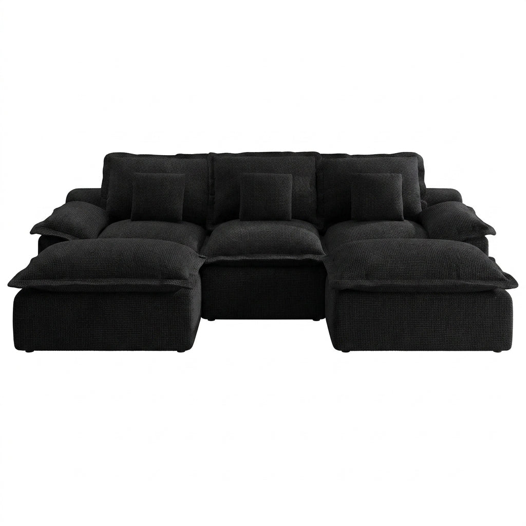 Modern black modular sectional sofa styled against a white painted brick wall with minimalist artwork and a round coffee table.
