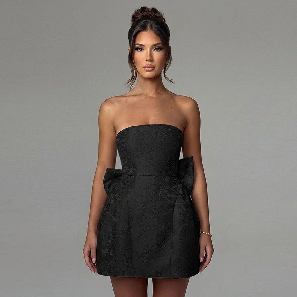 Close-up front view of the structured bodice and textured floral brocade fabric of the black strapless mini dress by Kouvr.