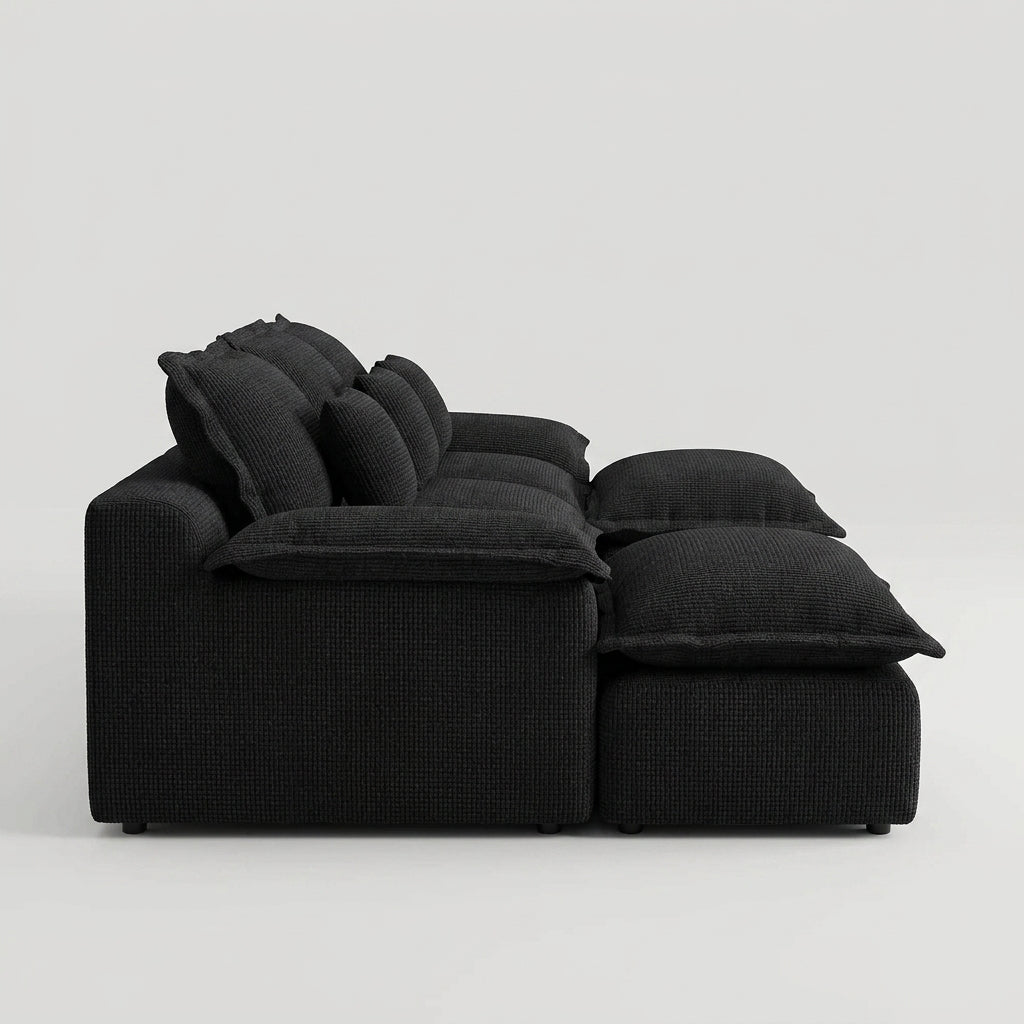Front view of a symmetrical black U-shaped modular sofa with plush cushions against a plain white wall.