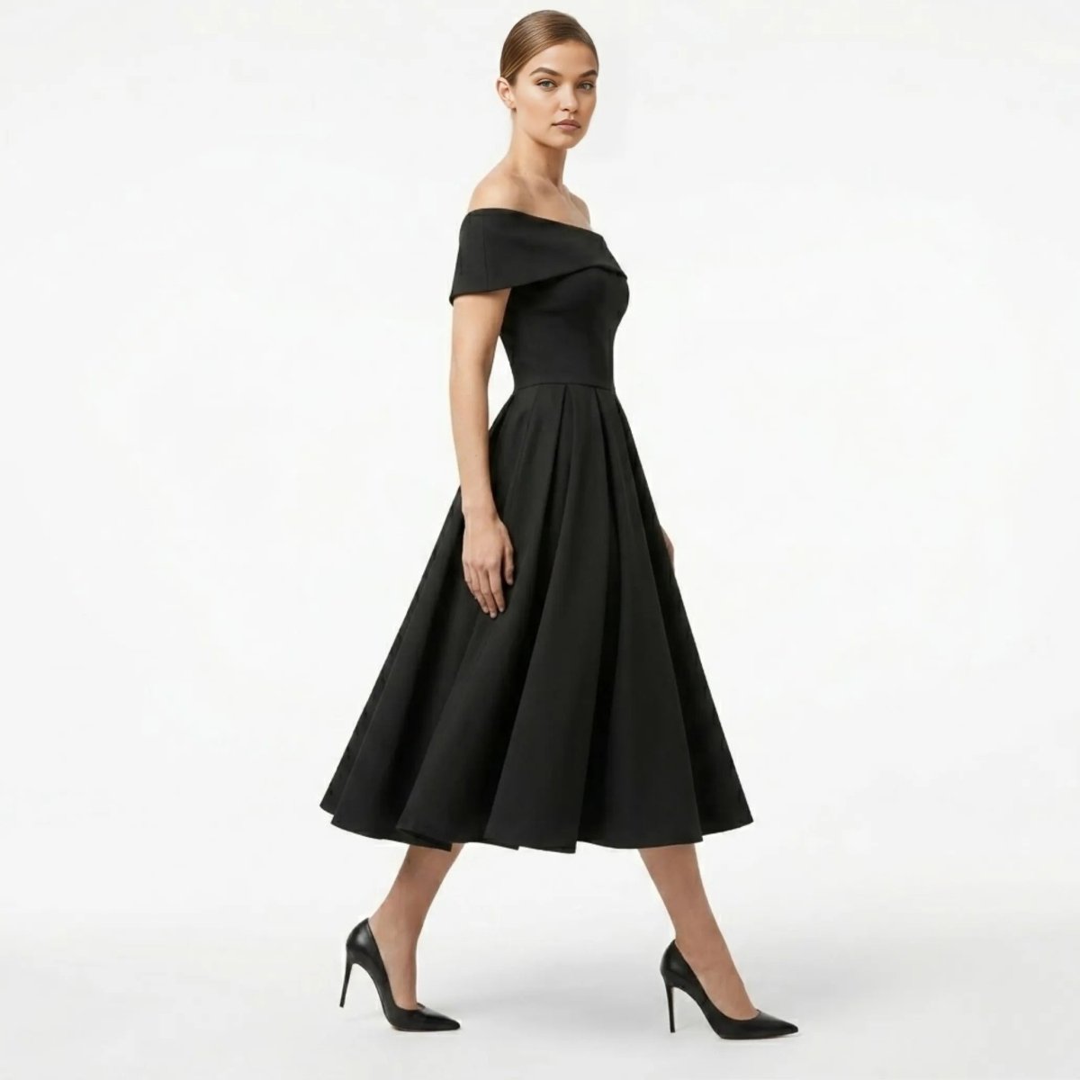 Side profile of a model wearing a fitted black vintage style cocktail dress showcasing the sweeping pleated skirt