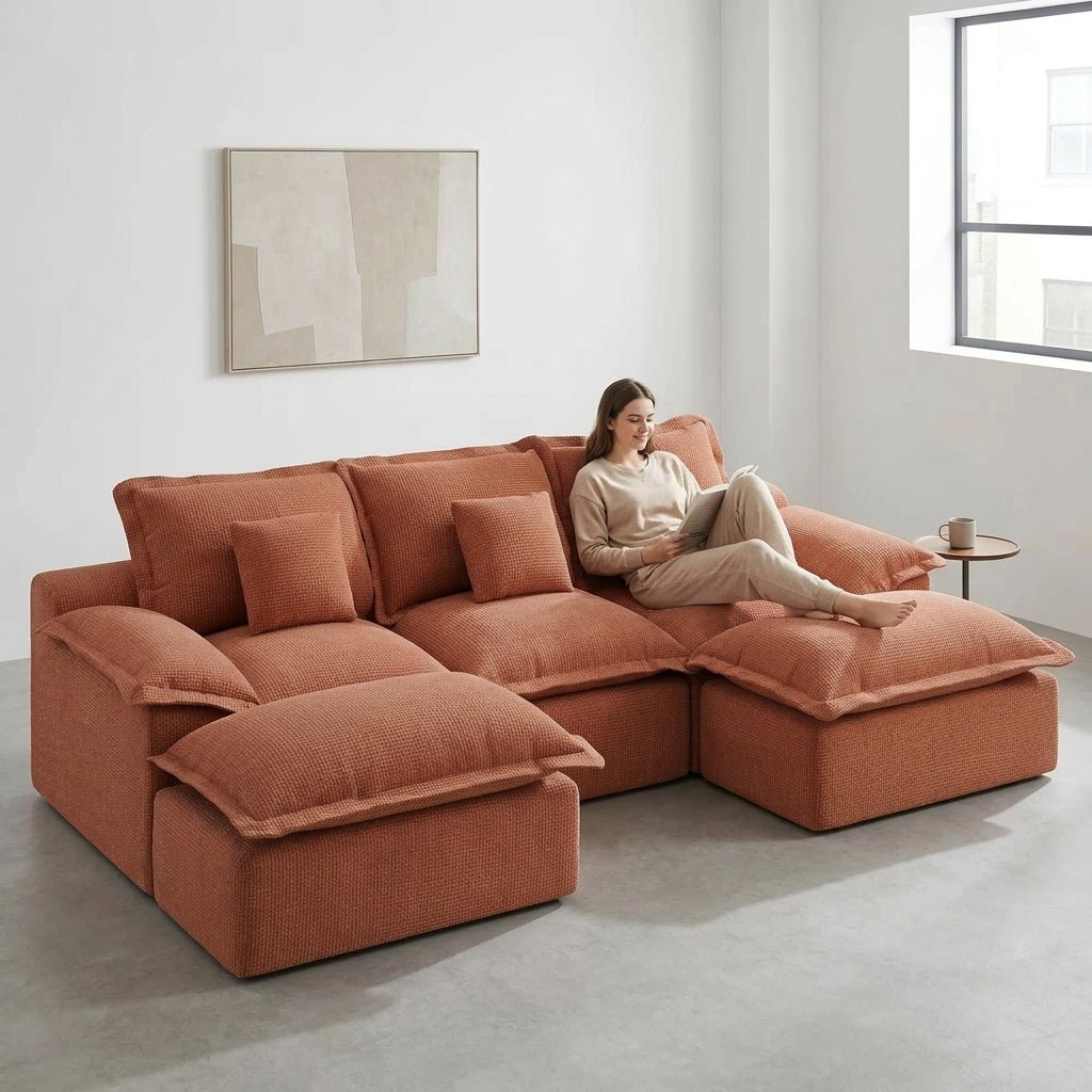 Symmetrical front view of a burnt orange U-shaped modular sectional sofa on a natural fiber rug.