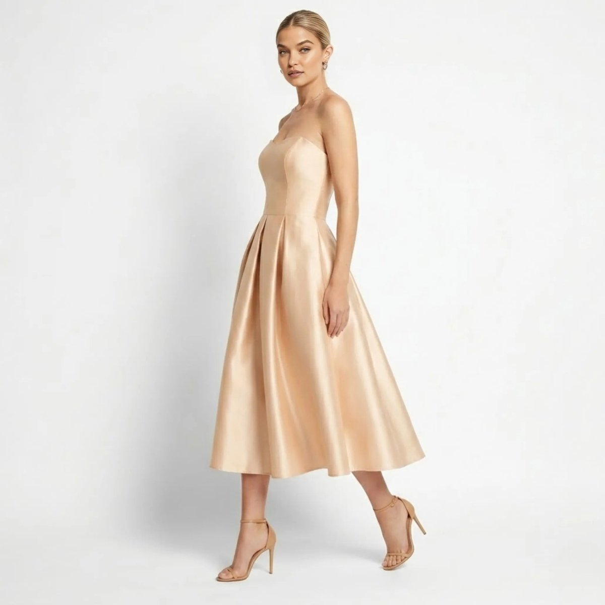 Side view of elegant champagne satin A-line cocktail dress with pleated midi skirt and strappy heels