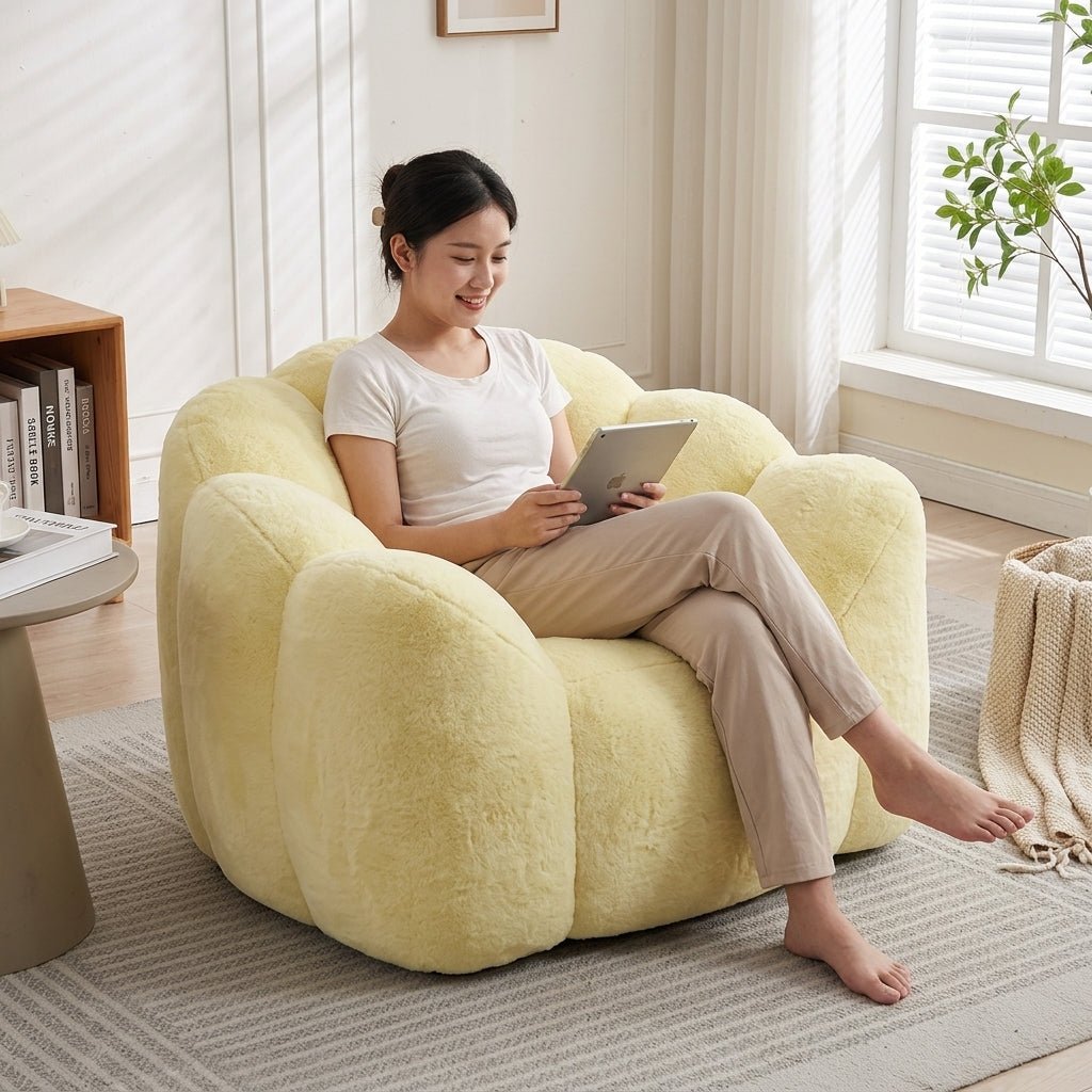 Front view of the fluffy yellow cloud reading chair illuminated by a warm floor lamp in a cozy moody room environment.