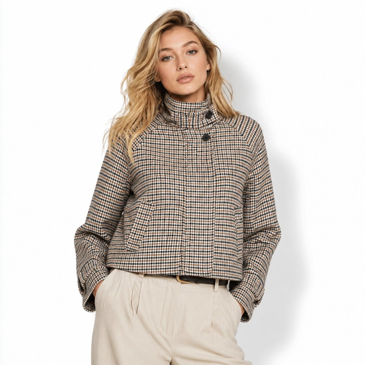Front view of a blonde female model wearing a cropped brown and black houndstooth jacket with a high collar and neutral tailored trousers.
