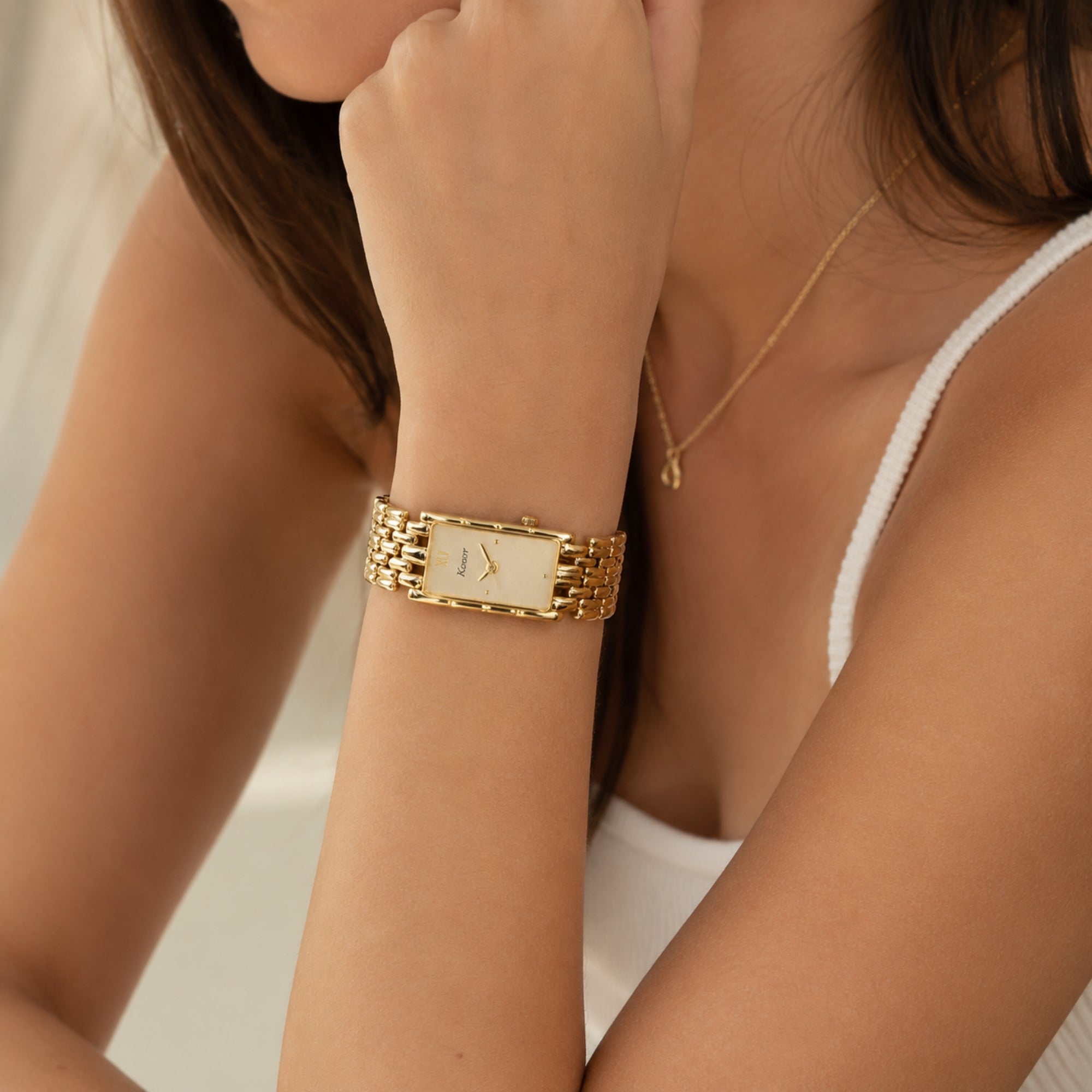Elegant woman wearing the Kouvr vintage style rectangular gold watch on her left wrist, showcasing its petite fit and seamless integration with everyday luxury fashion.