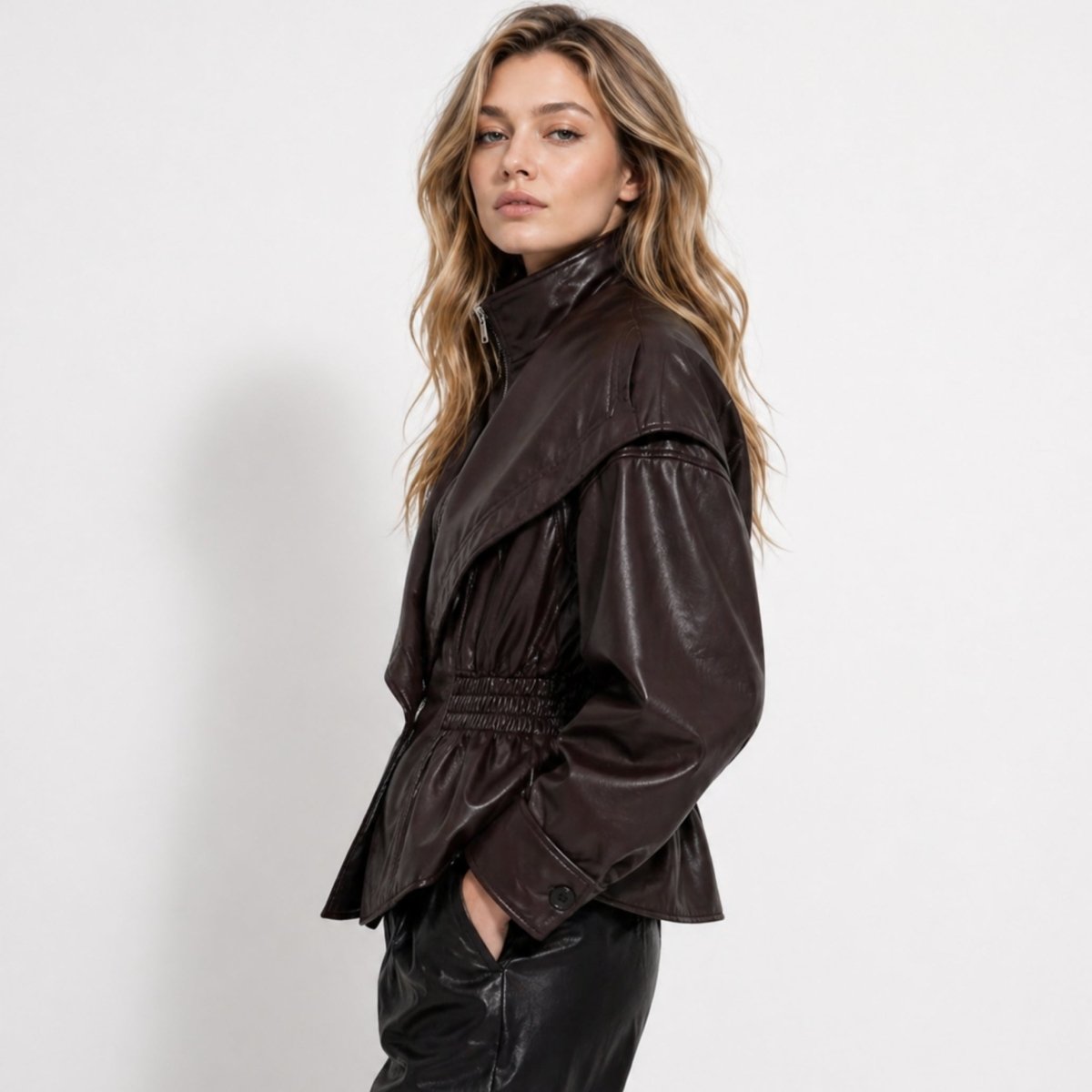 Side profile of woman wearing dark brown faux leather jacket with balloon sleeves and peplum hem.