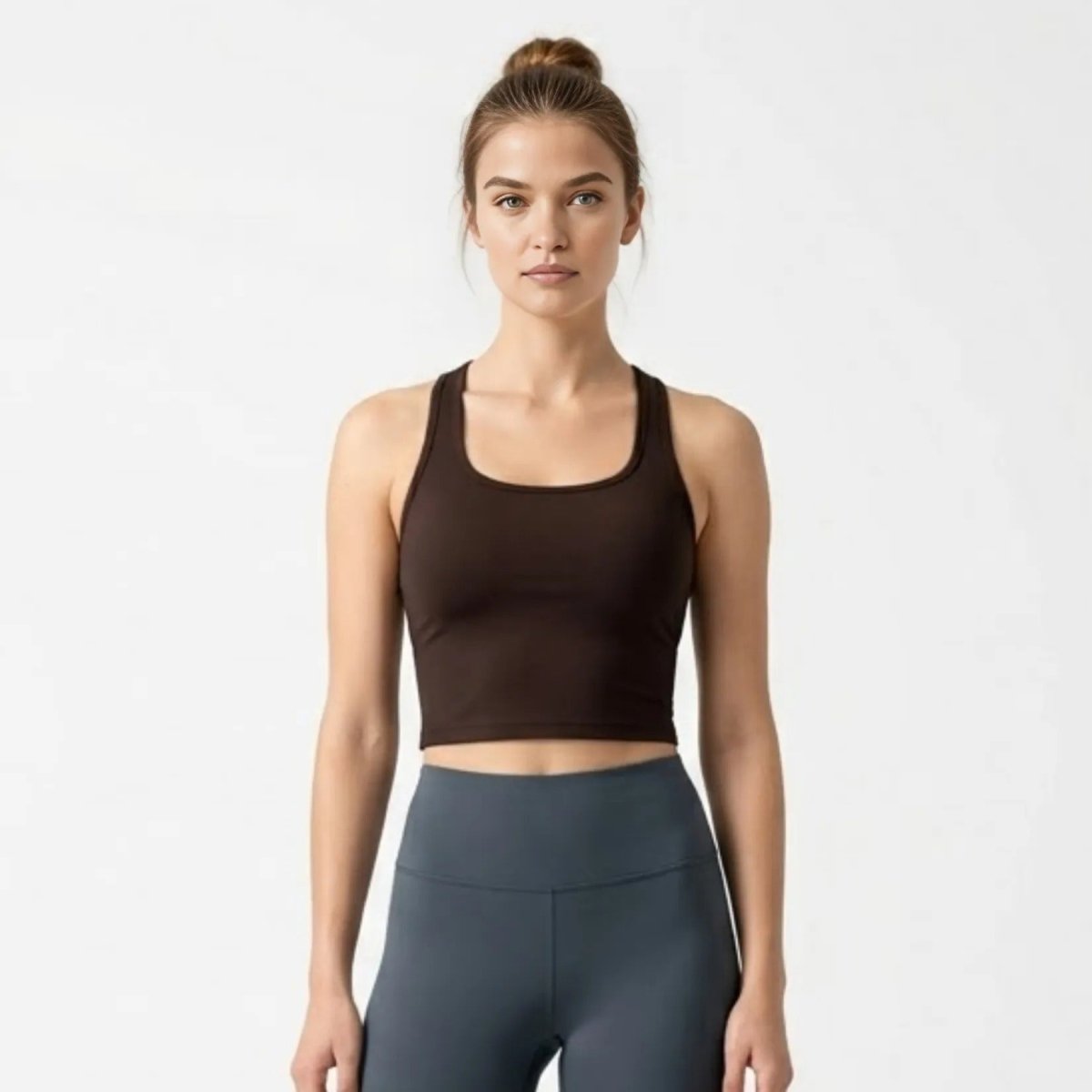 Woman wearing a dark brown scoop neck racerback cropped tank top looking forward.