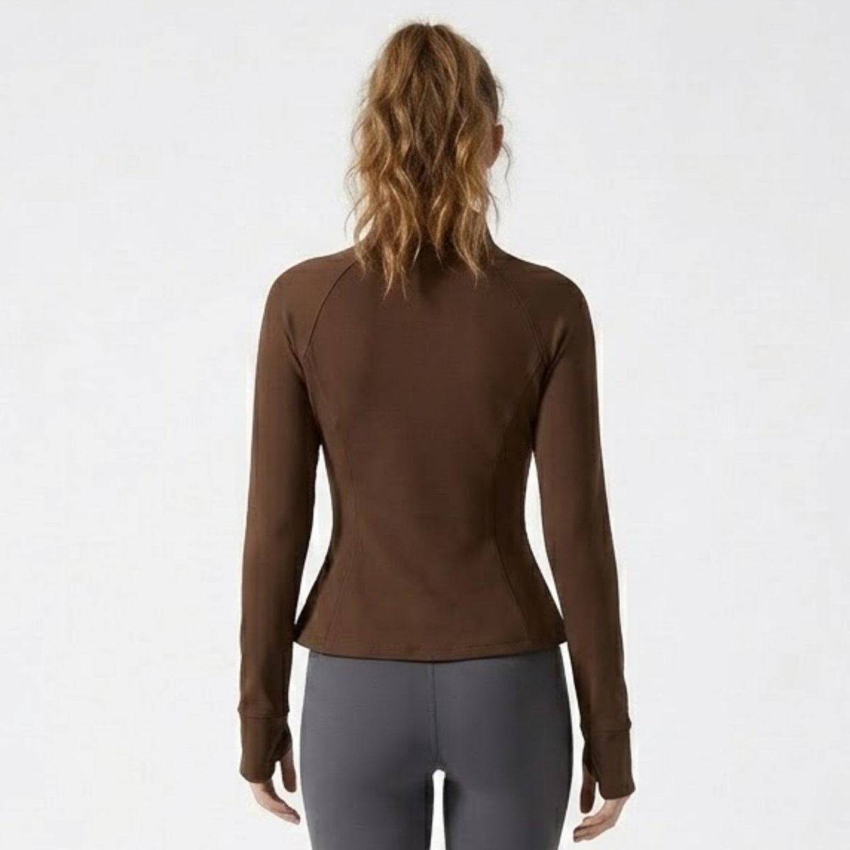 Back view of female model showcasing contouring waist seams on Kouvr brown athletic jacket