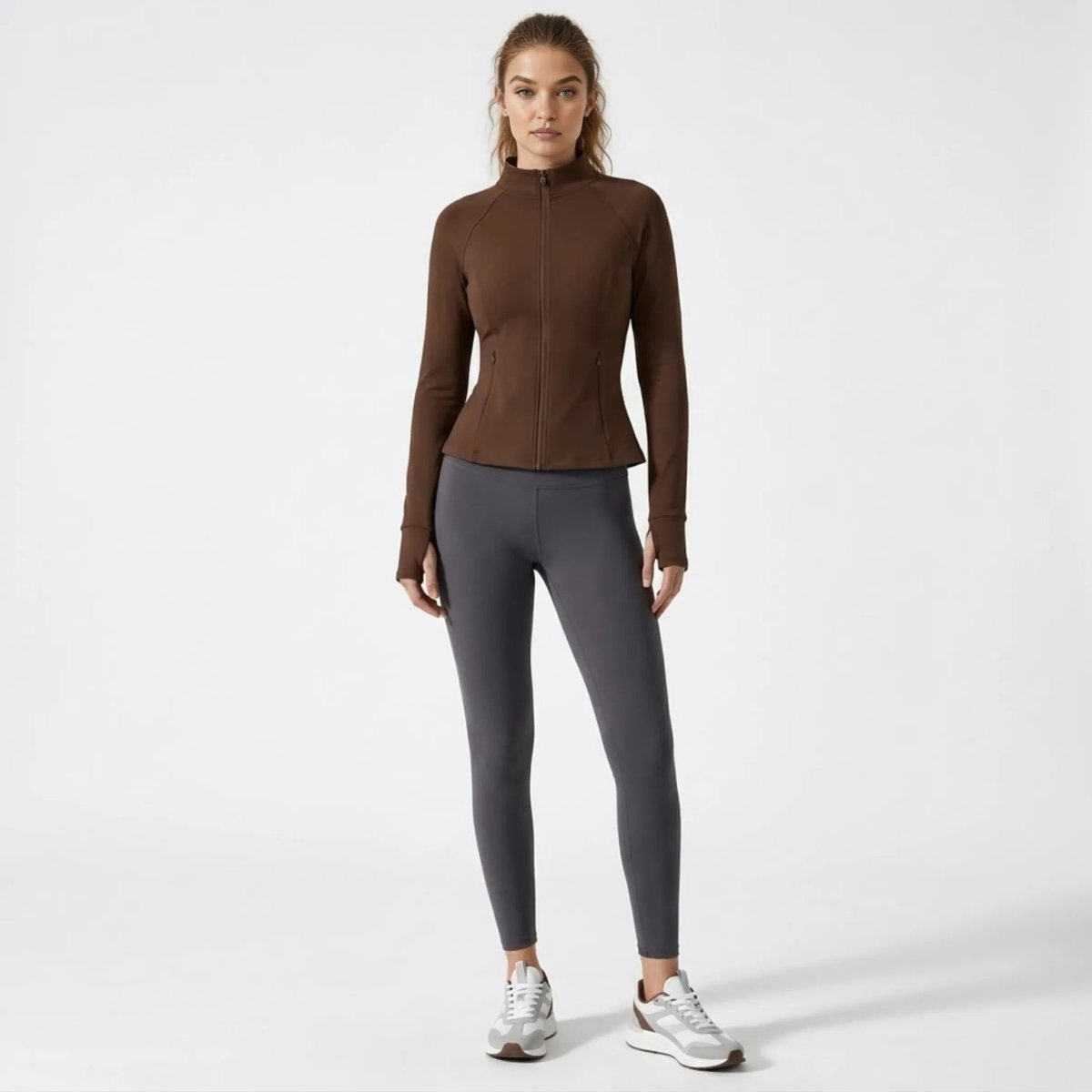 Full body view of female model in Kouvr luxury dark brown athleisure jacket and leggings with sneakers