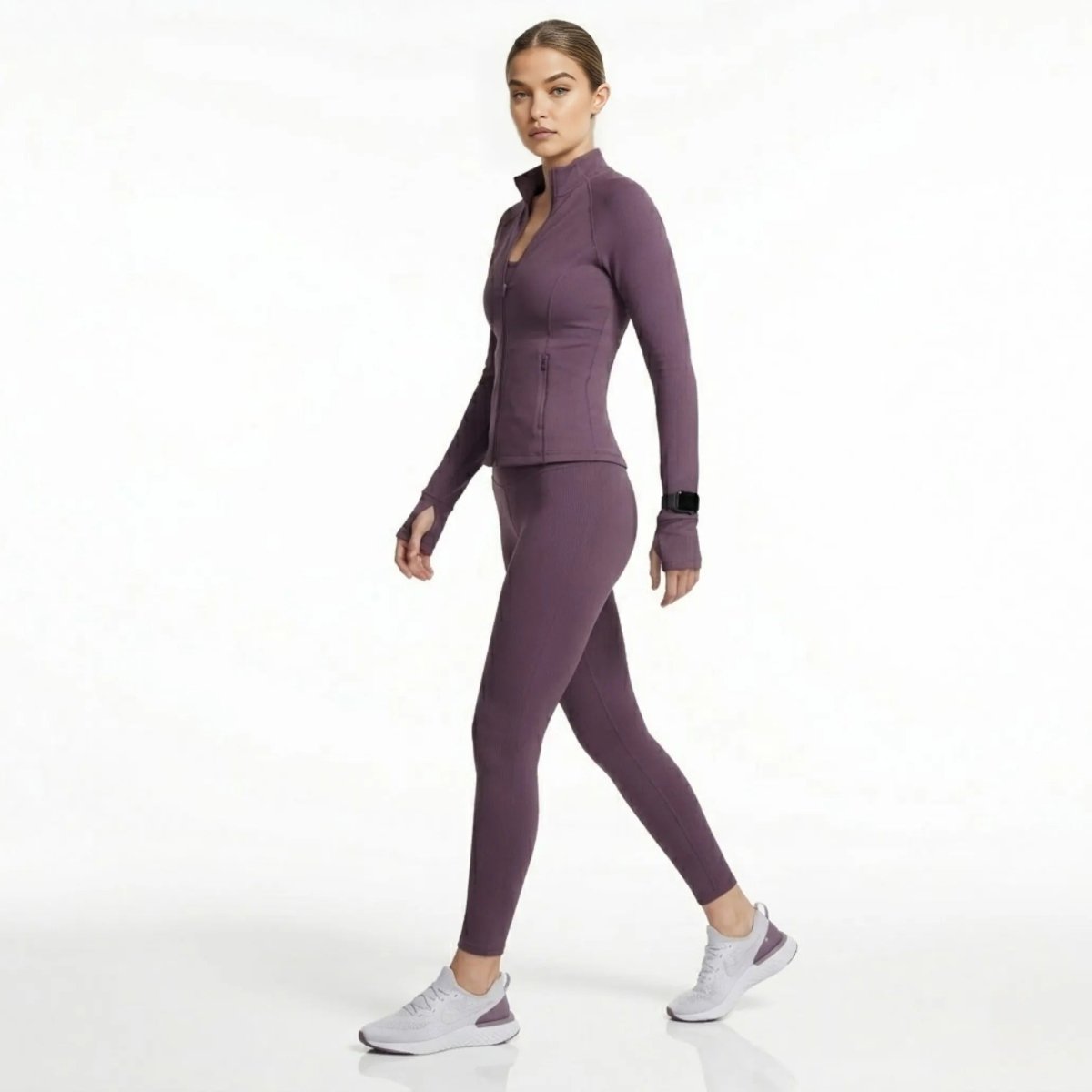 Back view of woman walking in Kouvr dark purple athletic track jacket and leggings