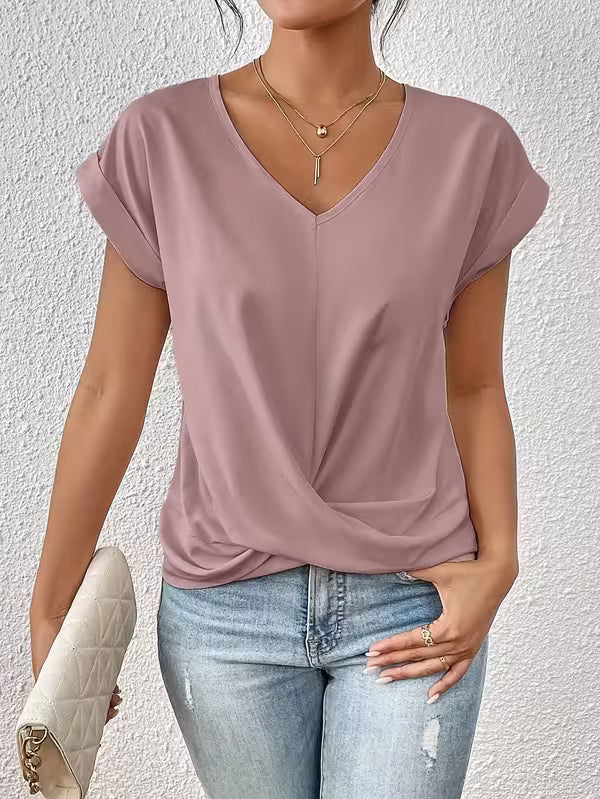 Woman wearing a pink top and blue jeans against a white wall