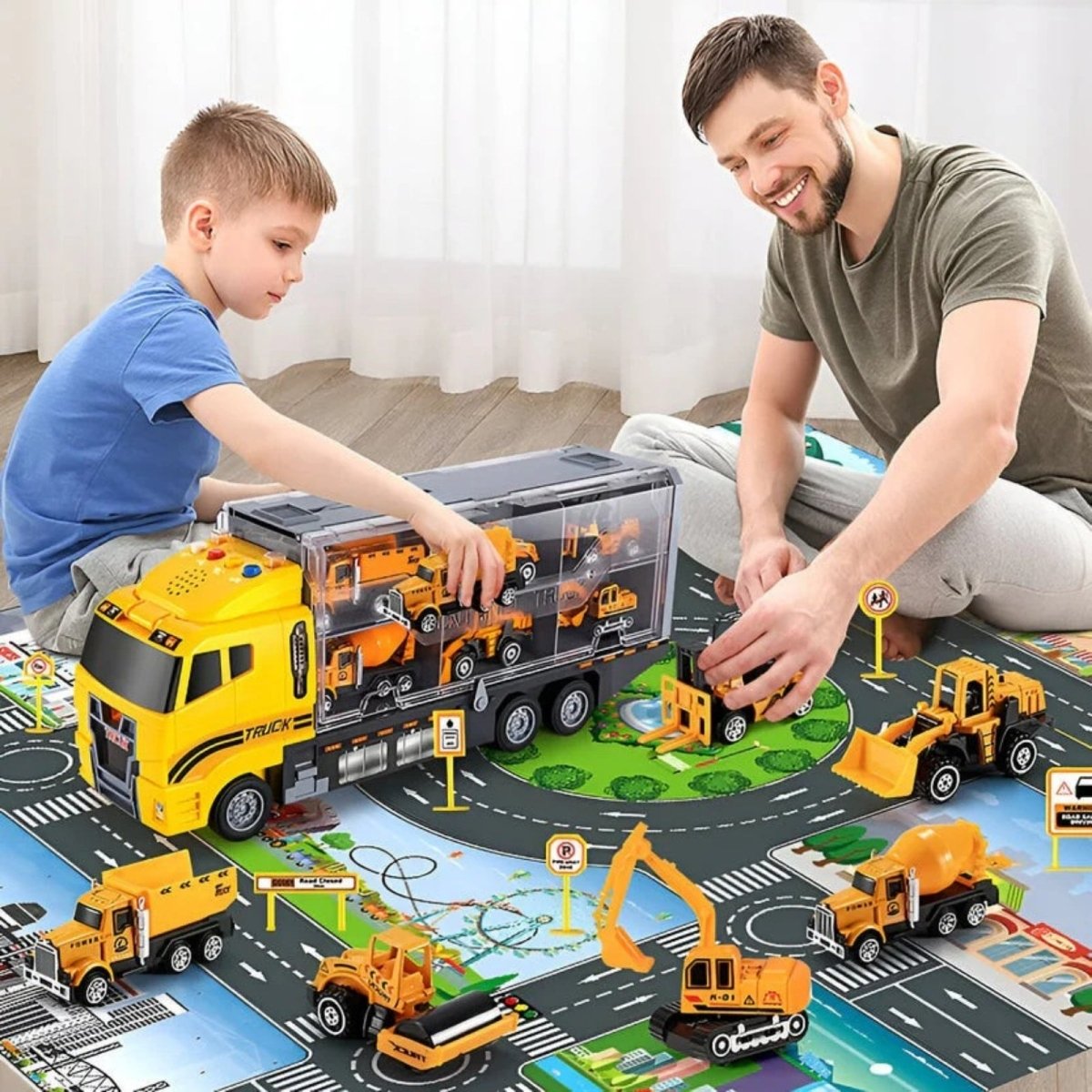 A father and son sitting on the floor together, playing with the Kouvr construction truck set and various vehicles on a city-themed play mat.