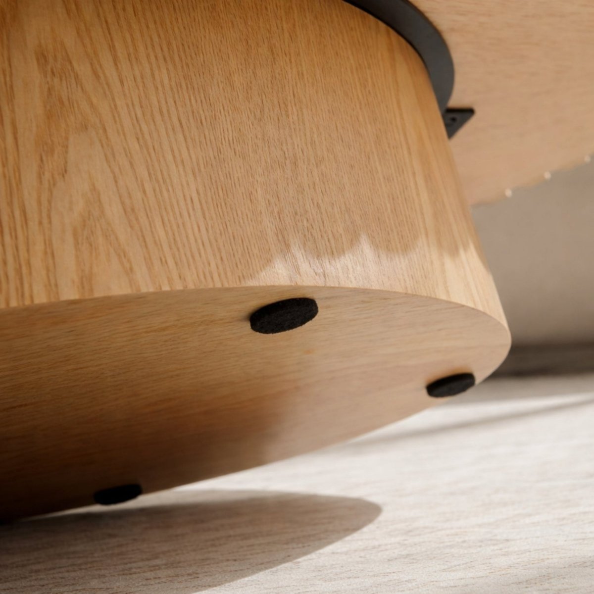 Underside of wood pedestal coffee table showing protective felt floor pads.