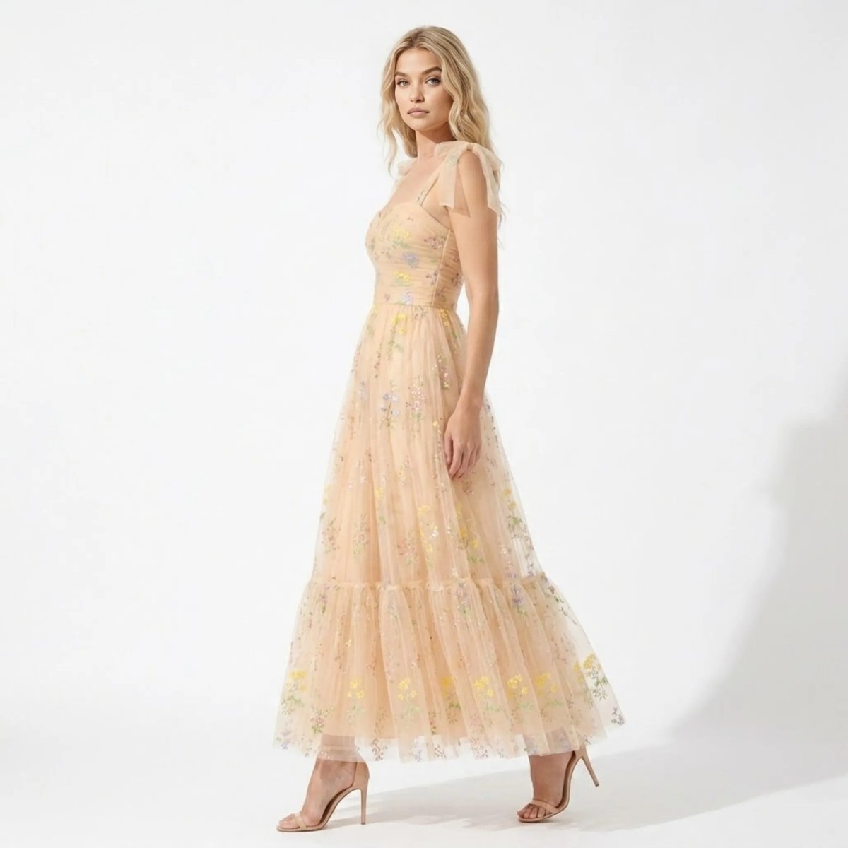 Side profile of elegant tiered tulle maxi dress with champagne floral embroidery and fitted bodice.