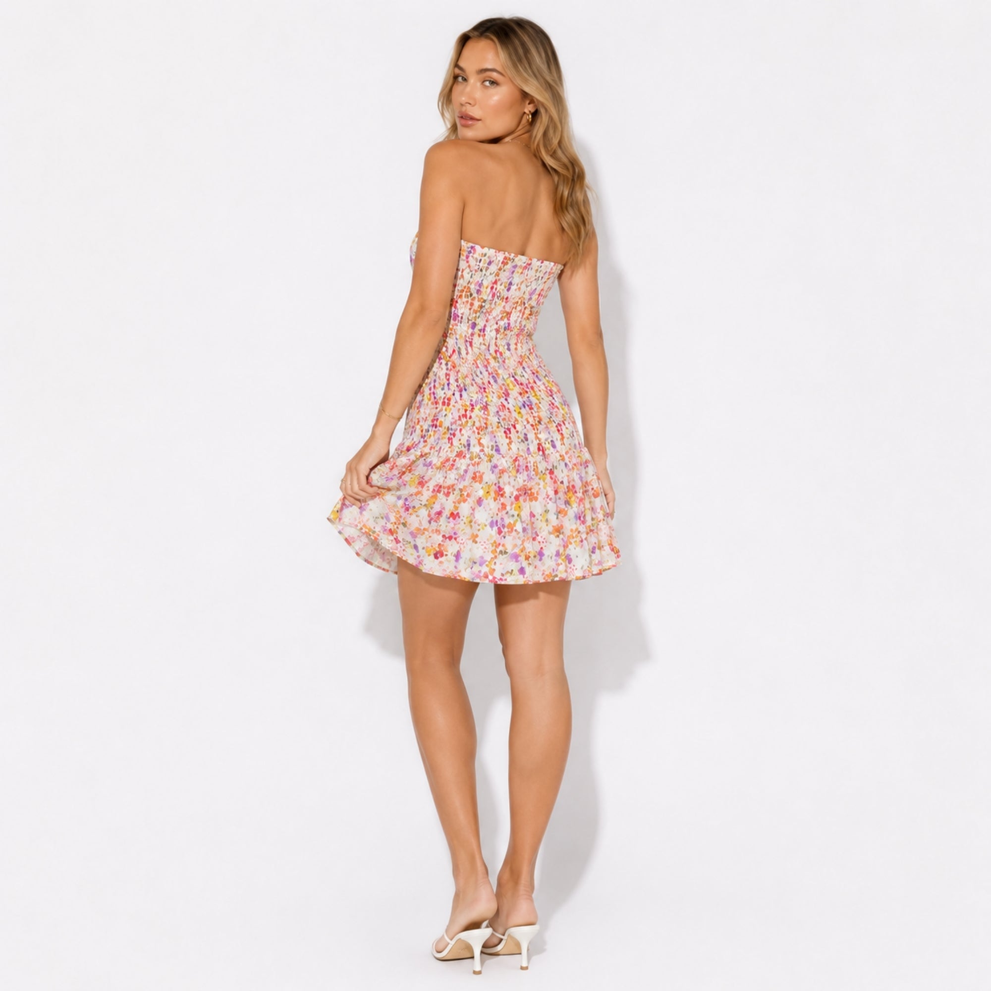 Back view of the floral strapless mini dress highlighting the continuous smocked detailing, secure fit, and bare shoulders. 