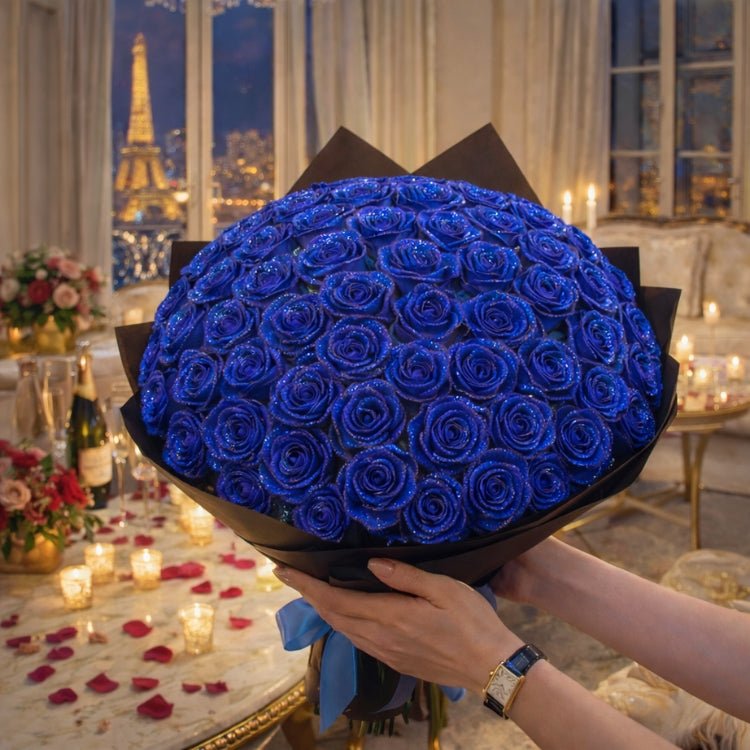A large, round bouquet of blue sparkle roses held against a romantic, candlelit background with a view of the Eiffel Tower at night.