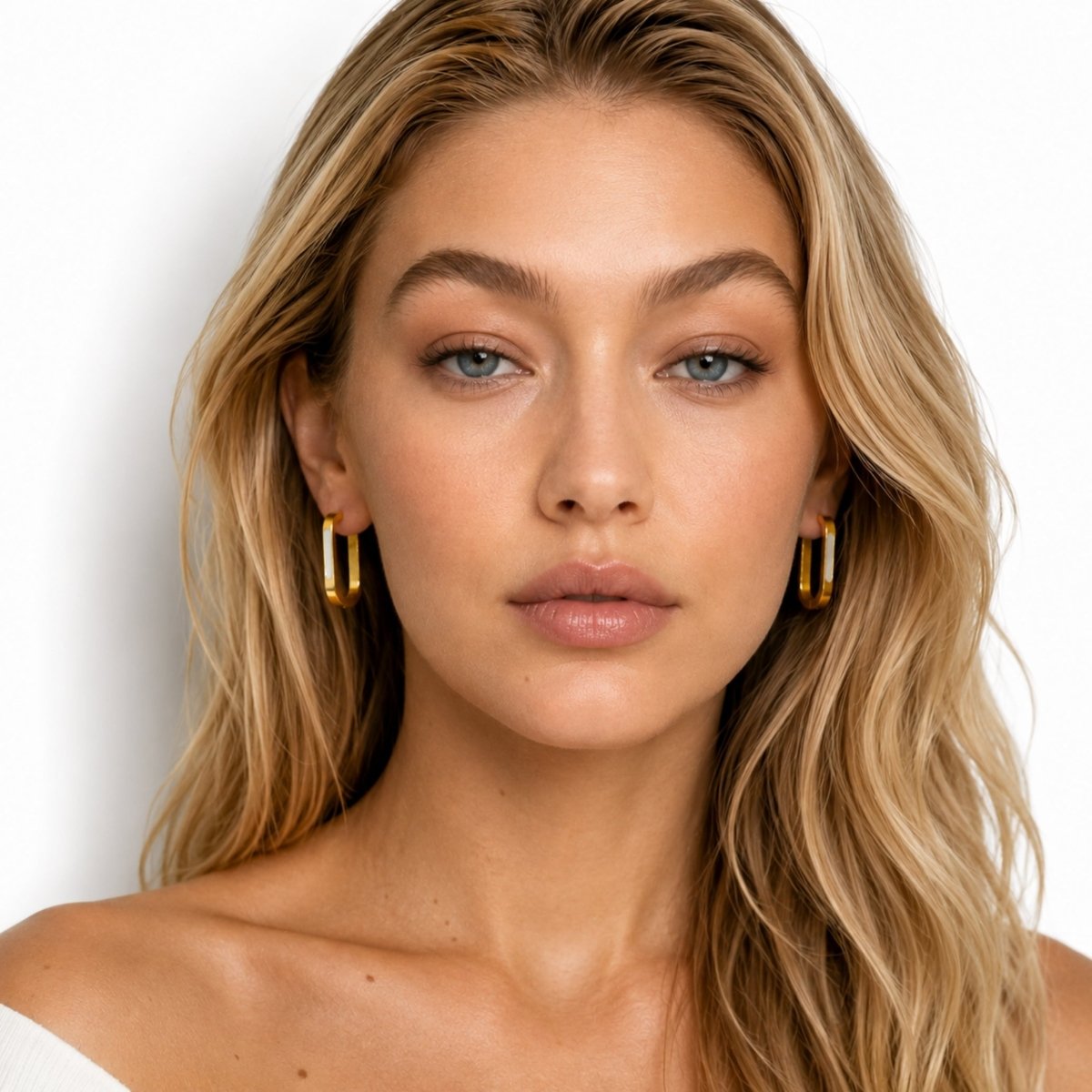 Premium gold rectangular hoop earrings resting elegantly on luxurious folded champagne silk fabric highlighting the polished finish.