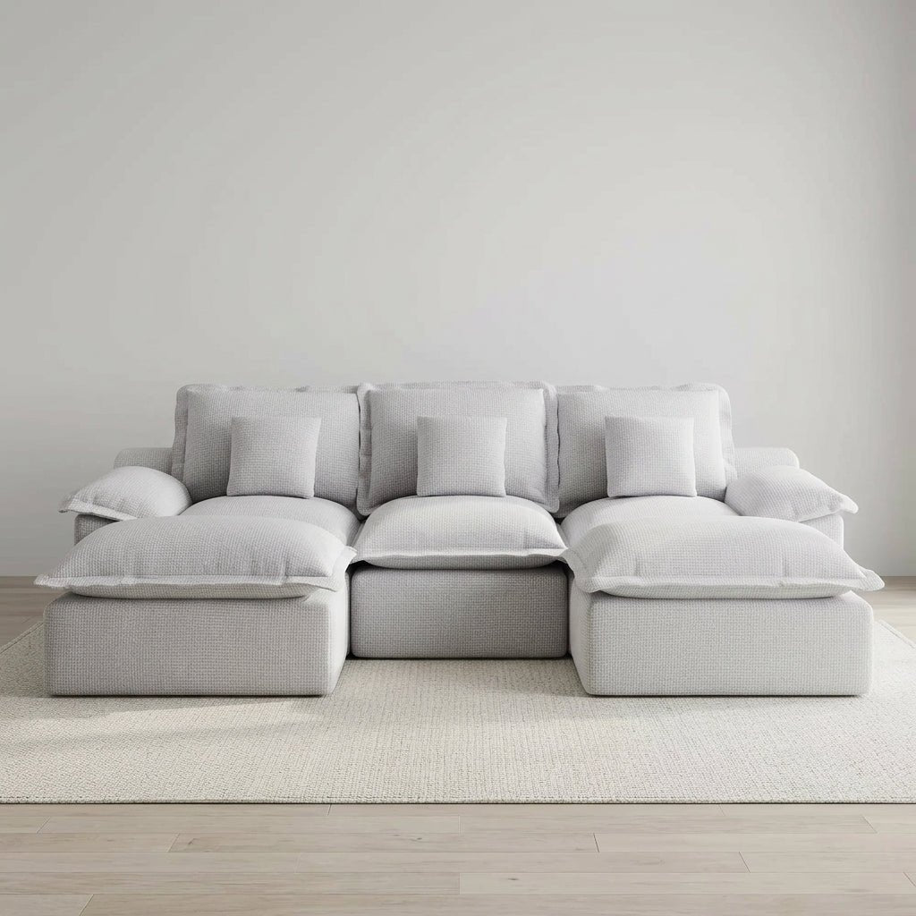Light grey modular sofa styled in a retro 70s-inspired room with wood paneling and a psychedelic orange rug.