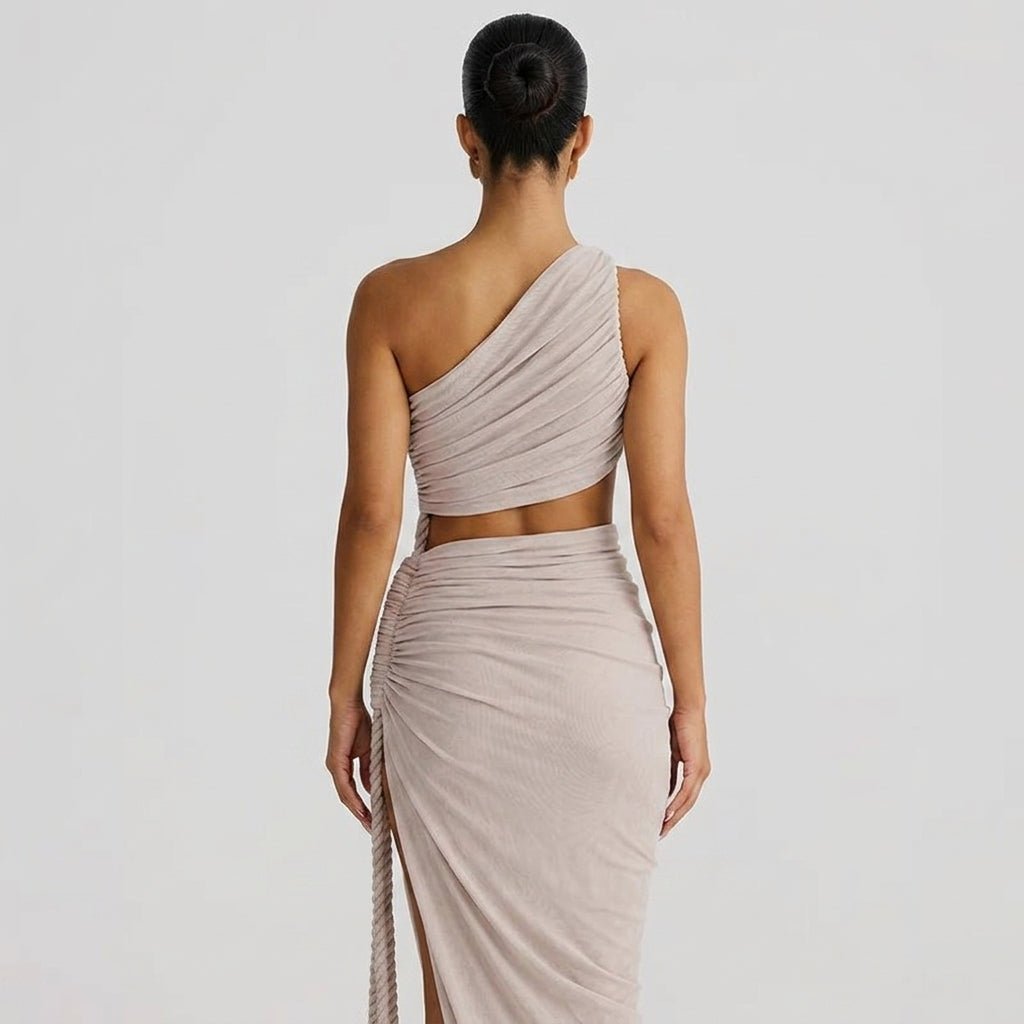 Back view of woman wearing an asymmetrical taupe draped maxi gown showing midriff cutout.