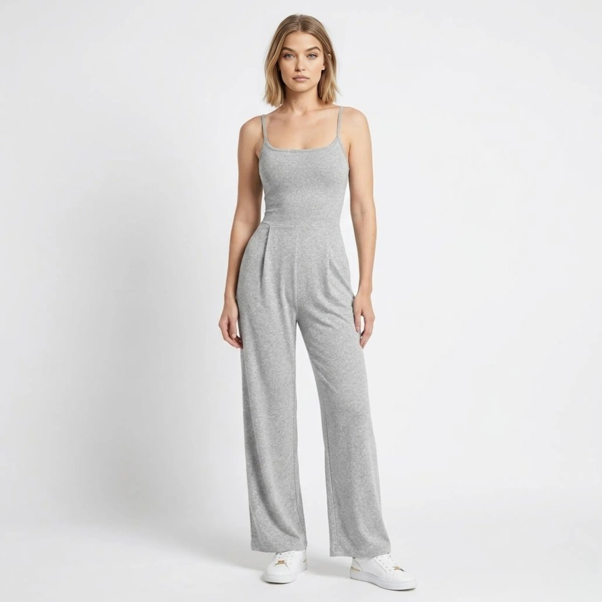 Woman wearing a light grey wide leg sleeveless knit jumpsuit with front pleats by Kouvr