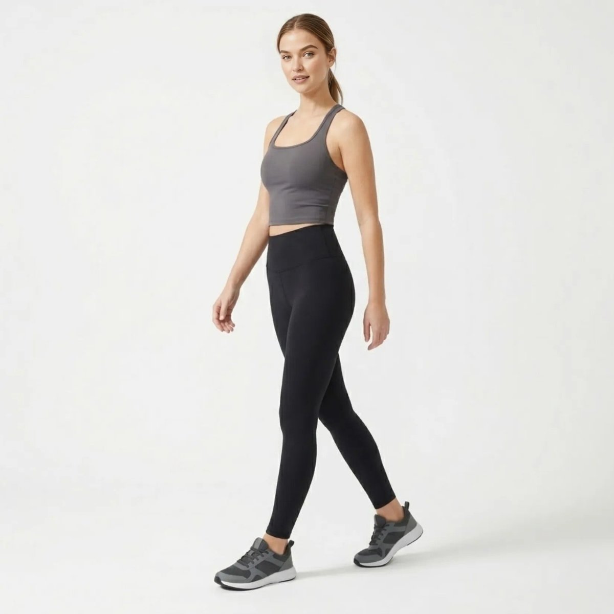 Side profile of woman walking in charcoal grey luxury athletic crop top and black leggings.