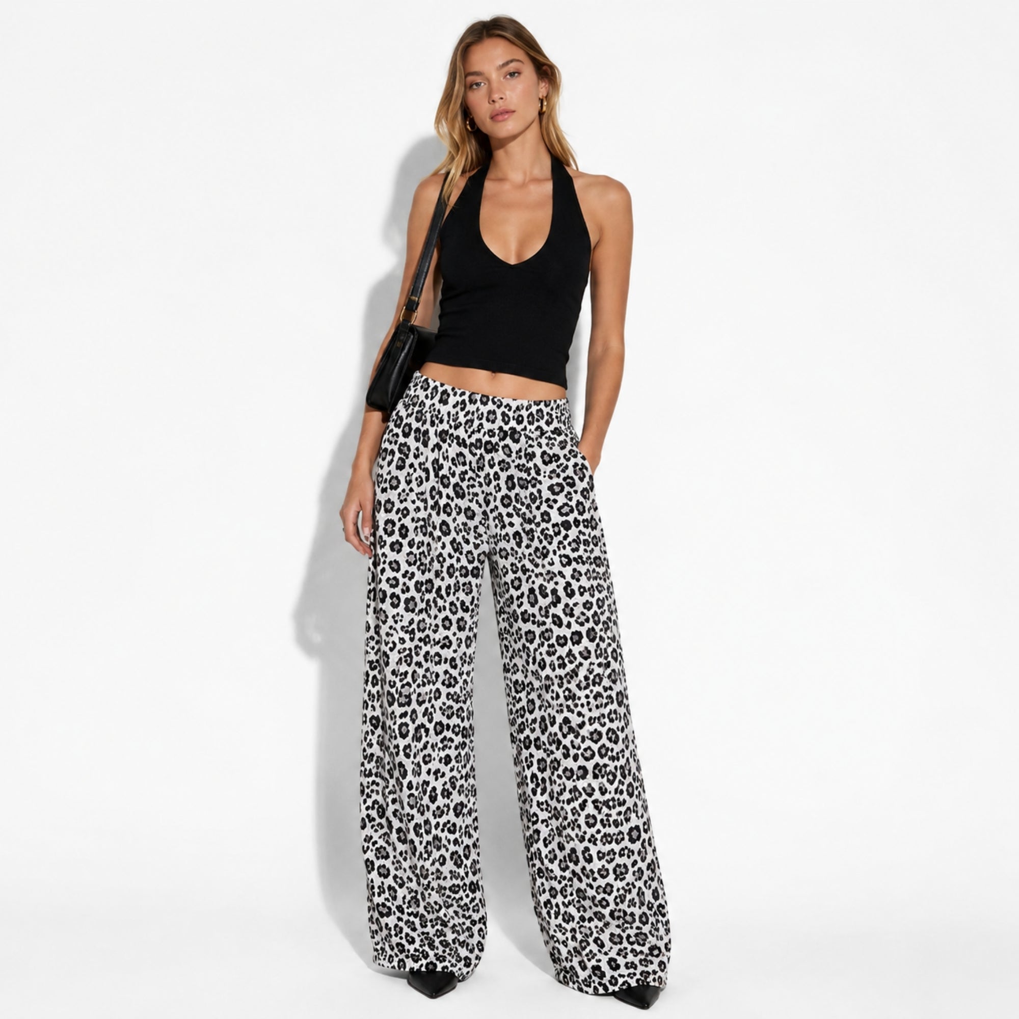 Model wearing leopard print wide leg palazzo trousers with a black halter top and pointed shoes for a chic outfit