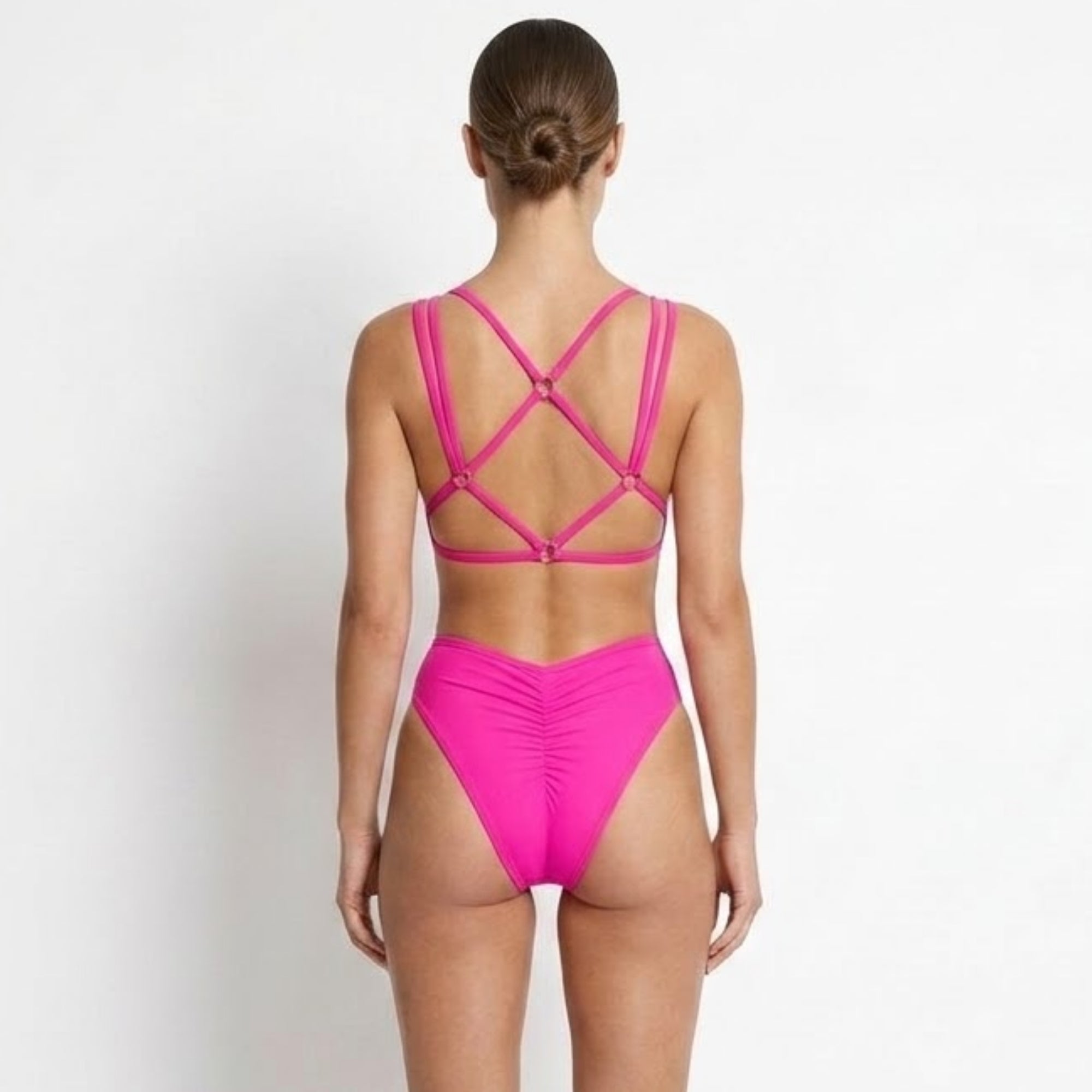 Detailed back view of the hot pink swimwear showing the supportive cage back design and flattering ruched cheeky cut.