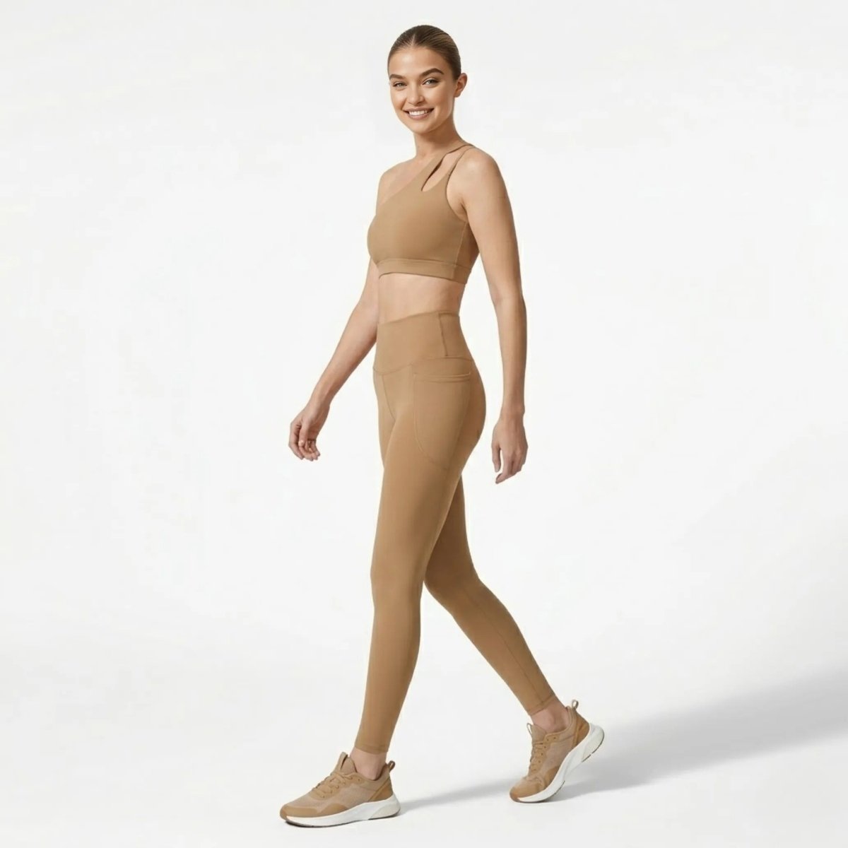 Side profile of woman walking in Kouvr khaki high waisted workout leggings with side pockets and matching one shoulder top