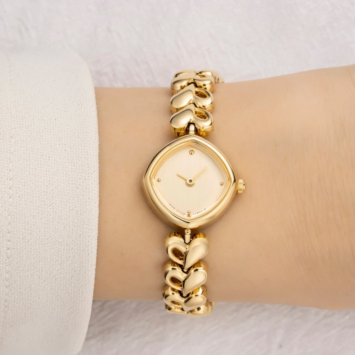 Hand wearing gold kouvr rings with a brown background