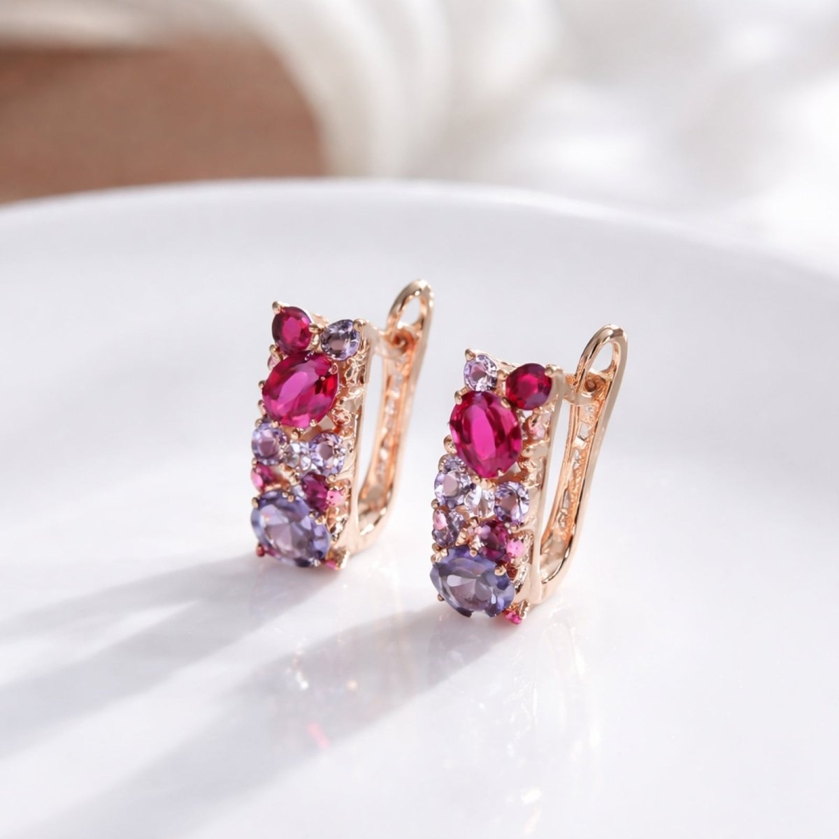 Front view of the Kouvr Aileen pink and purple zircon cluster earrings on a white surface with soft, natural lighting.