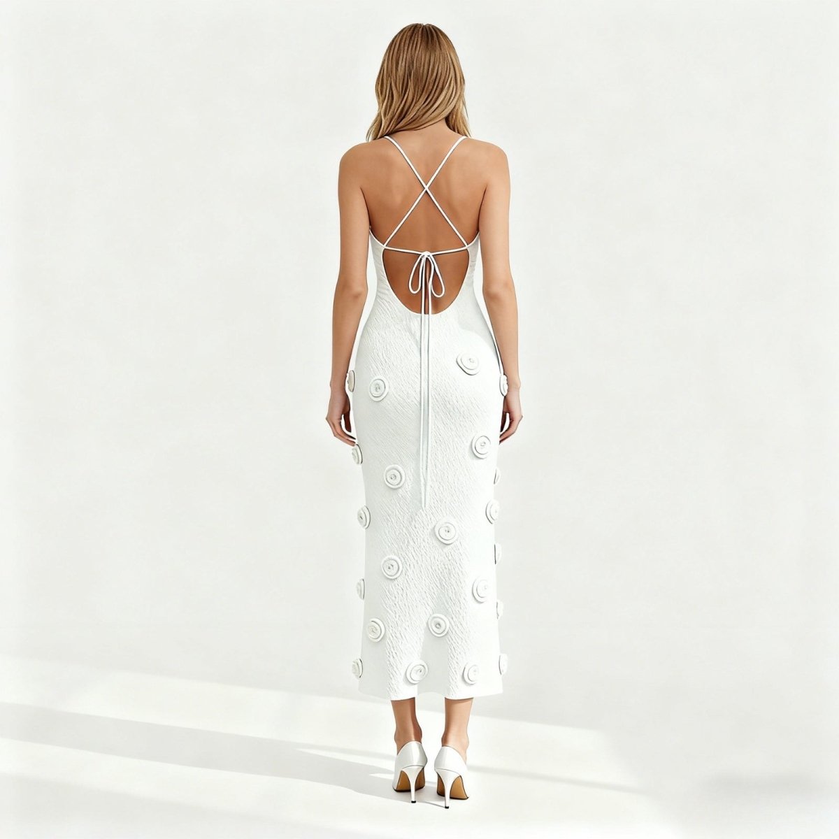 Woman wearing a white dress with floral patterns on a plain background