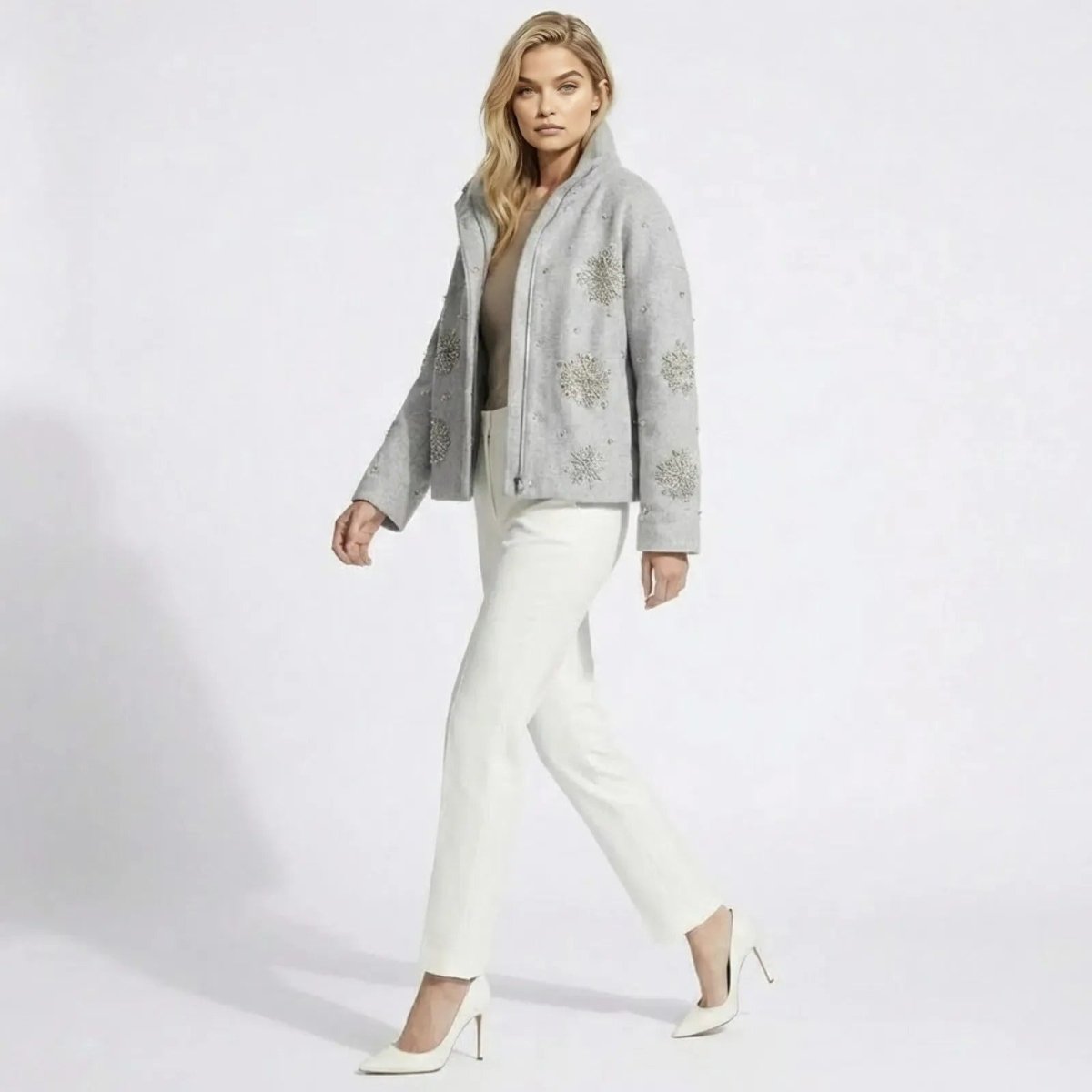 Model walking and showing the side profile and sleeve detail of the Kouvr Alisa light grey wool jacket with hand-beaded crystal snowflakes.