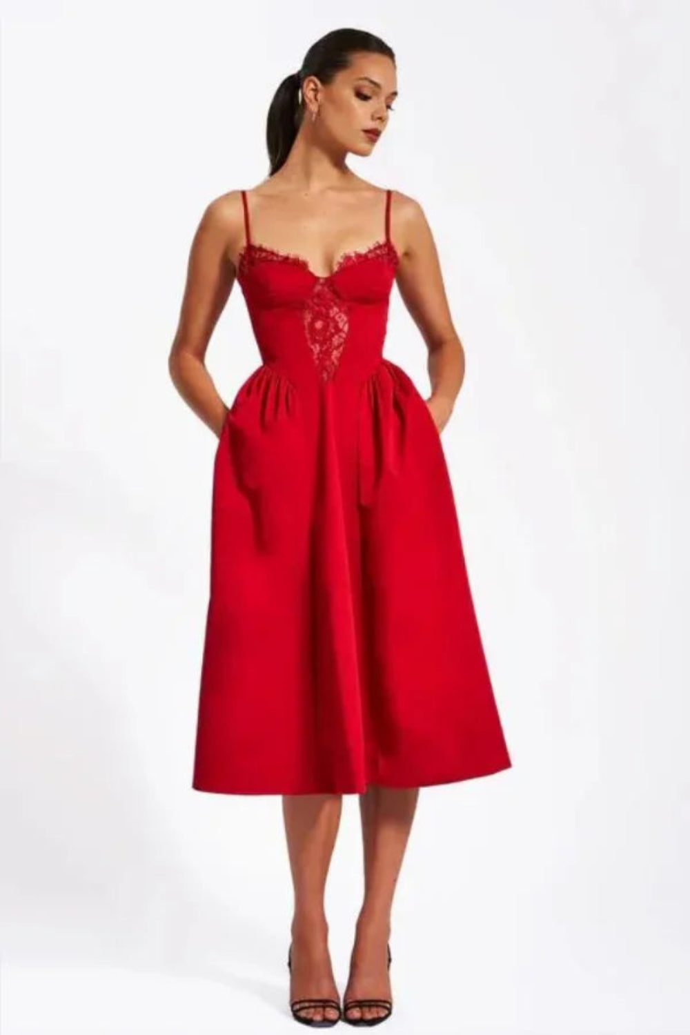 Model wearing Kouvr Amadi red corset midi dress with lace detail and hands in pockets