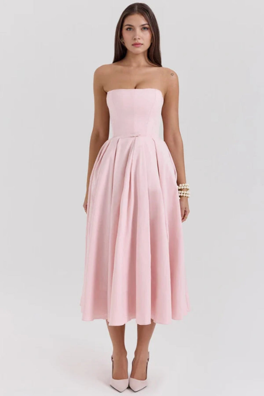 Model wearing the Kouvr Fashion blush pink strapless midi dress with a full pleated skirt
