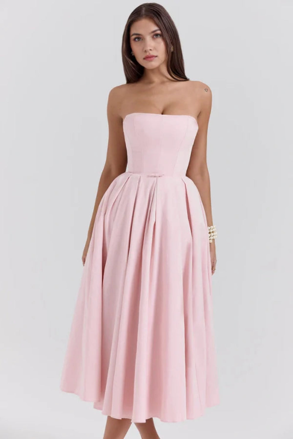 Model wearing the Kouvr Fashion blush pink strapless midi dress with a full pleated skirt