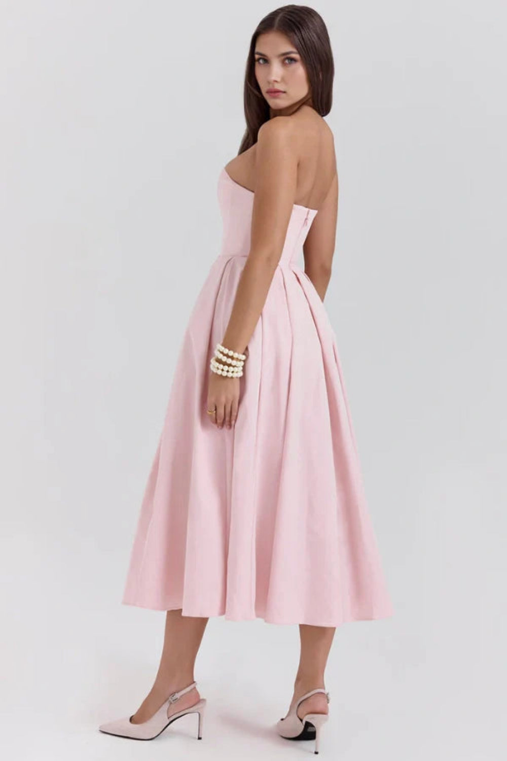 Model wearing the Kouvr Fashion blush pink strapless midi dress with a full pleated skirt