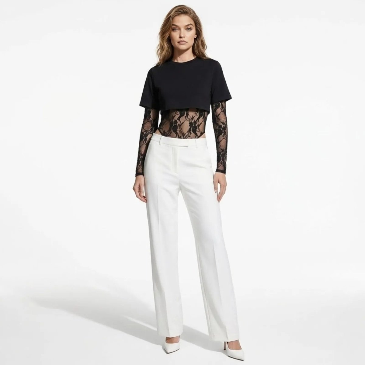 Model facing forward wearing the Angelique layered black lace and t-shirt bodysuit from Kouvr Fashion paired with white trousers.
