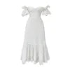 Model wearing the Kouvr Annie white eyelet midi dress on a balcony overlooking the ocean