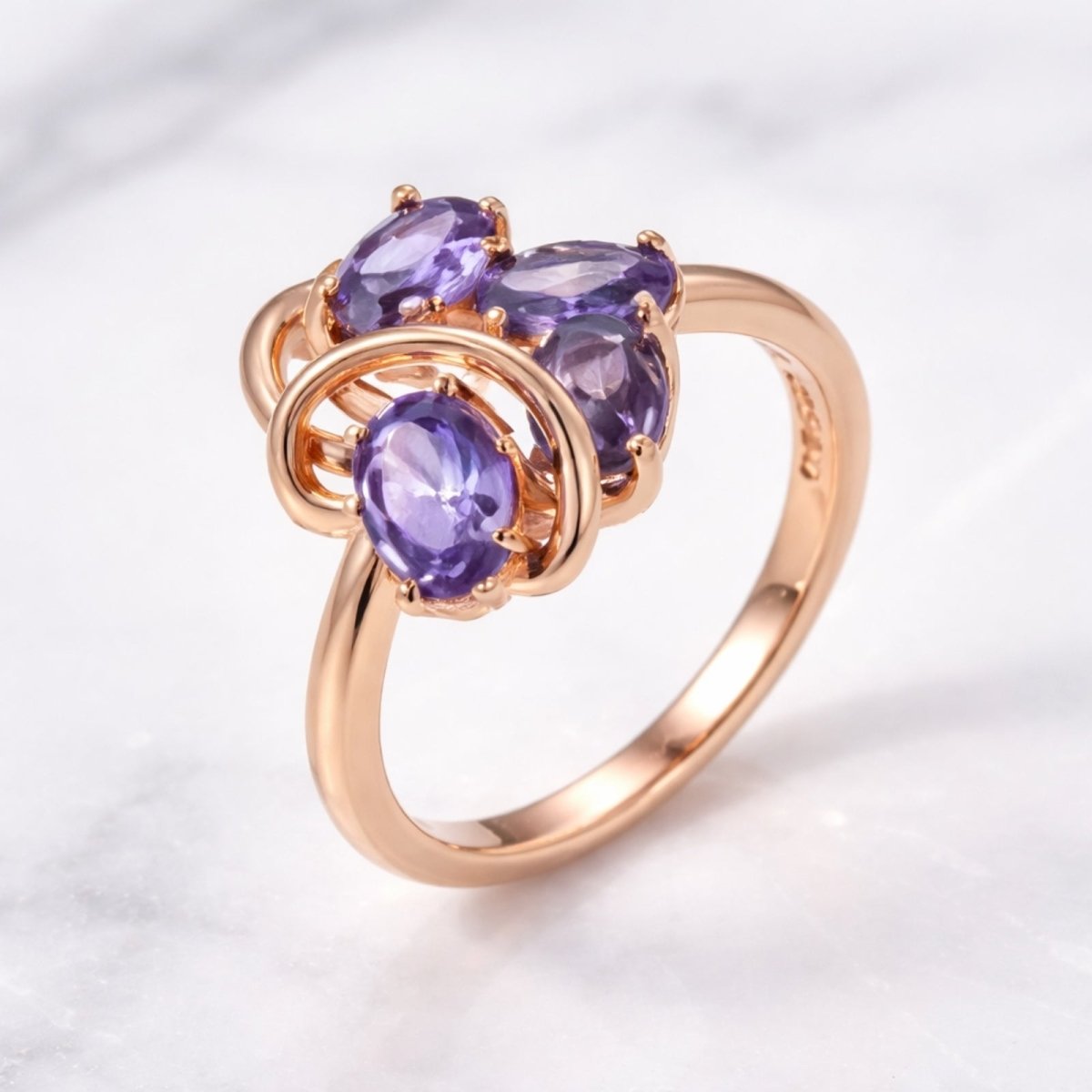 The Kouvr Annika purple zircon ring styled on a white marble surface, emphasizing its luxurious quality and warm rose gold tone.