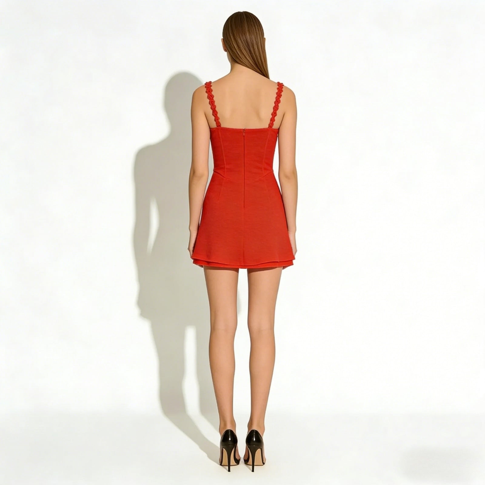 Back view of a model wearing the Kouvr Ariadne red mini dress, showing the scalloped straps and concealed zipper detail.